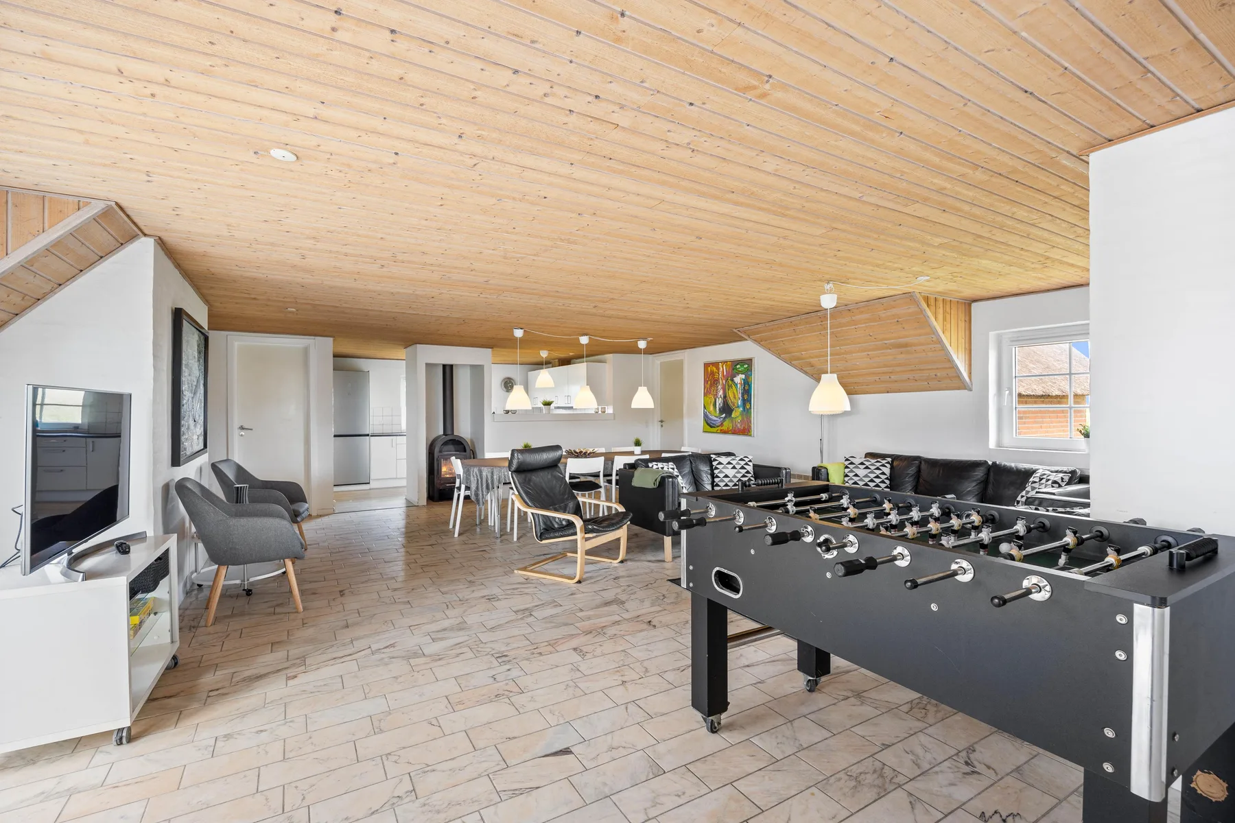 A living and dining area with seating and a foosball table.