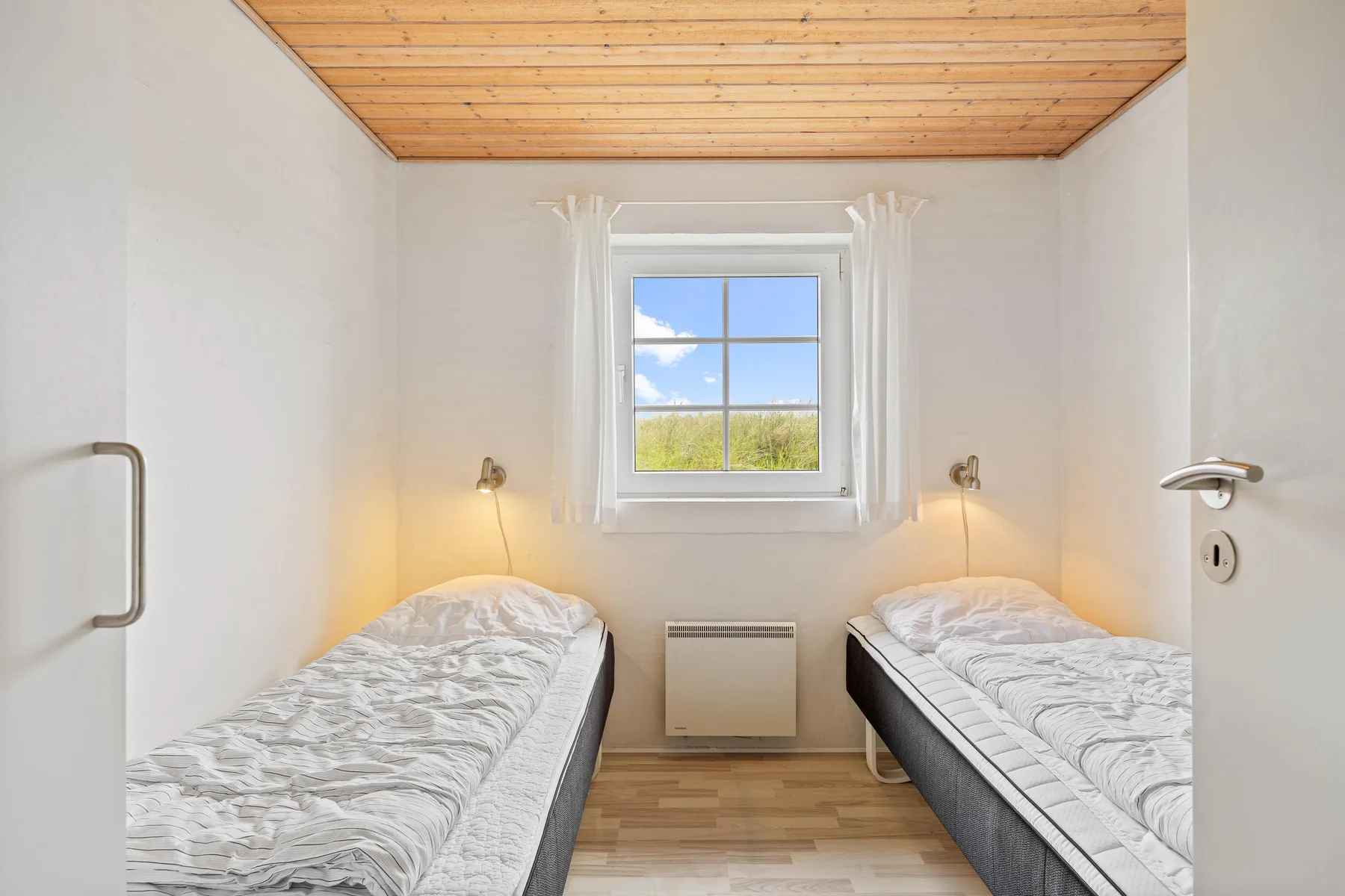 A bright bedroom with two single beds and a window.