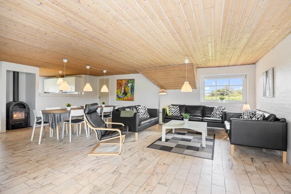A bright open-plan living room with seating, a dining table, and a kitchen.