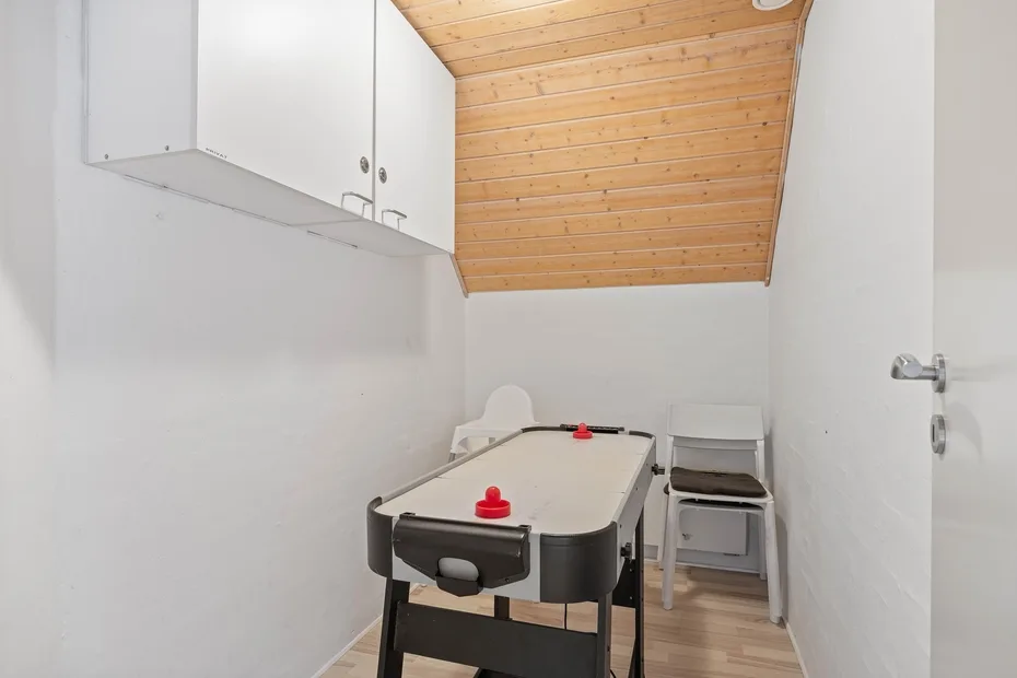A narrow game room with a table football game beneath a sloped wooden ceiling.