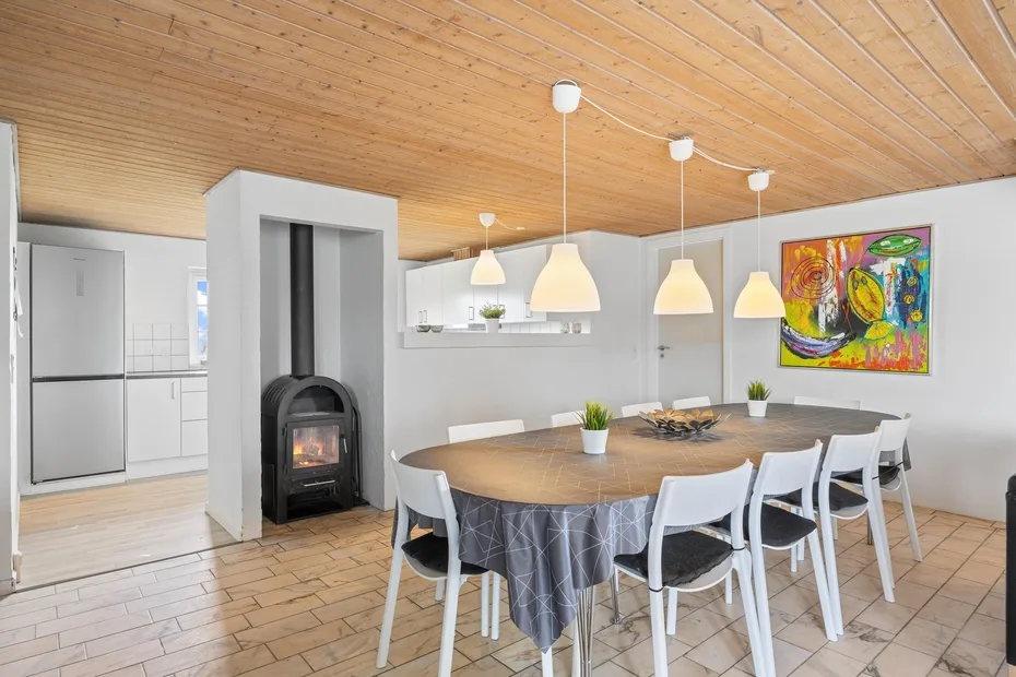 A dining area with a large table, chairs, and pendant lights.
