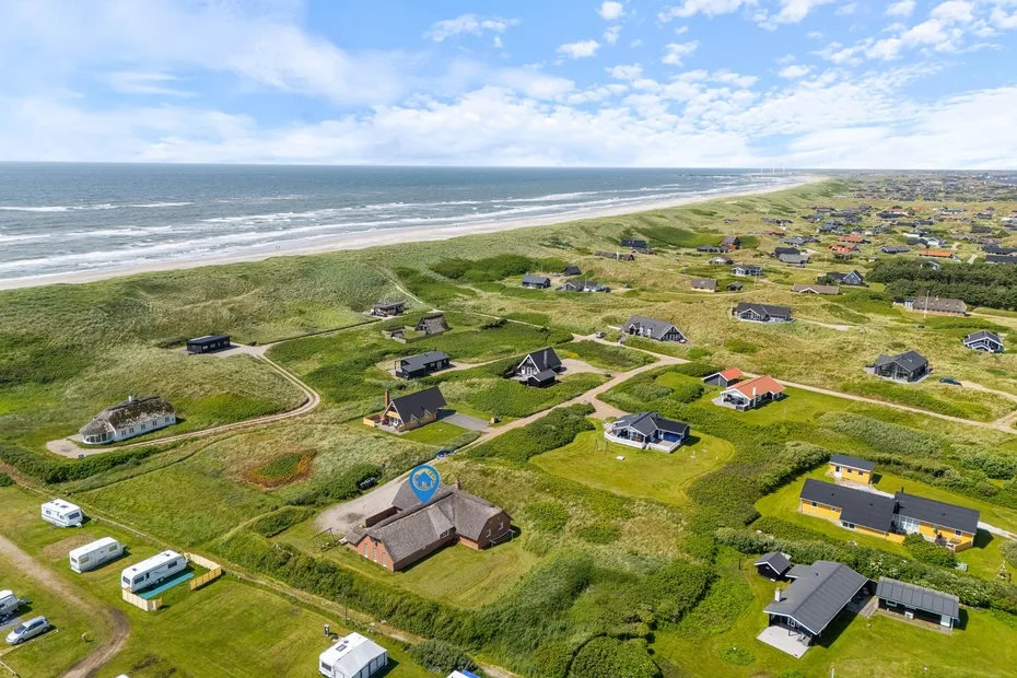 Aerial view of a coastal settlement with scattered houses beside the shoreline.