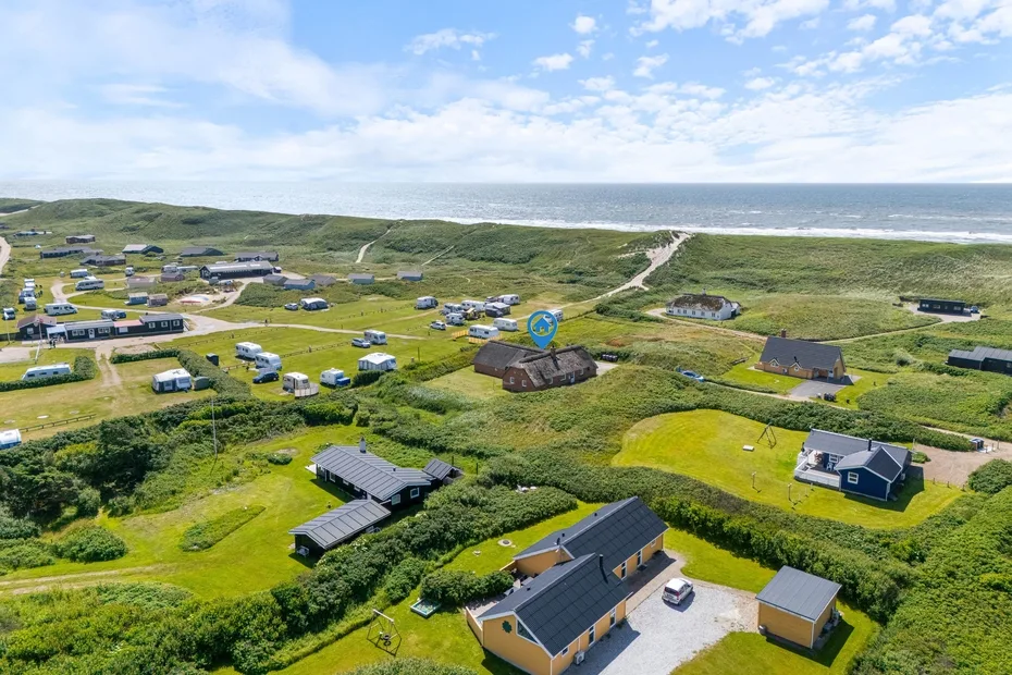 Aerial view of a coastal campground with scattered buildings and the ocean beyond.