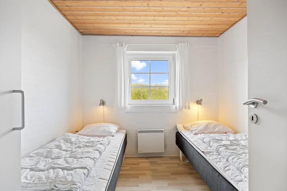 A small bedroom with two single beds beneath a window.