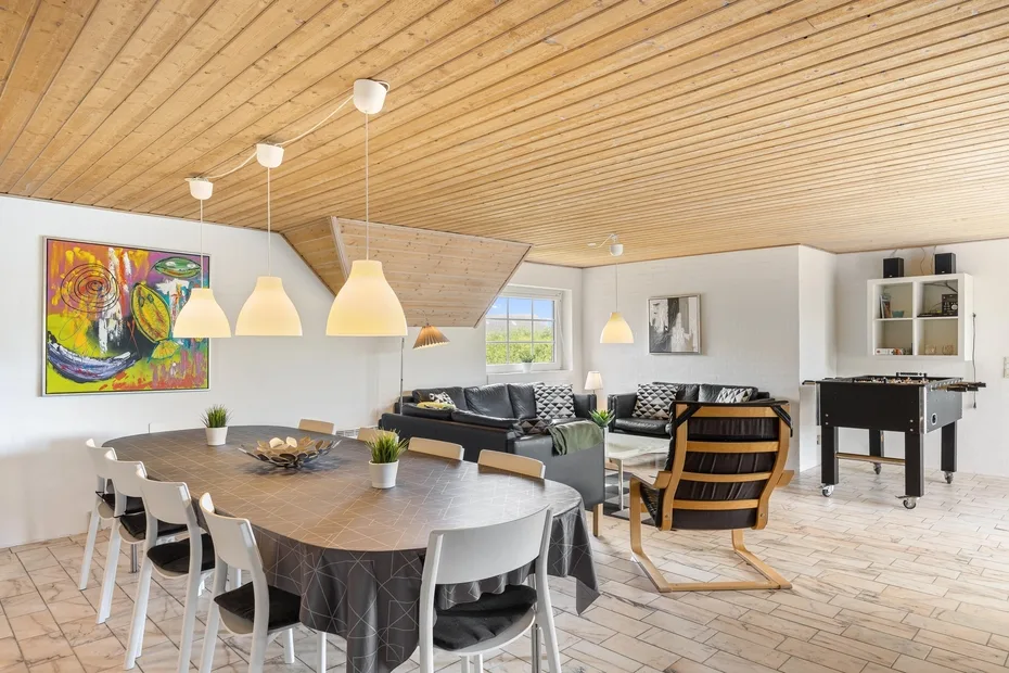 A dining and living area with a large table, seating, and a pool table.