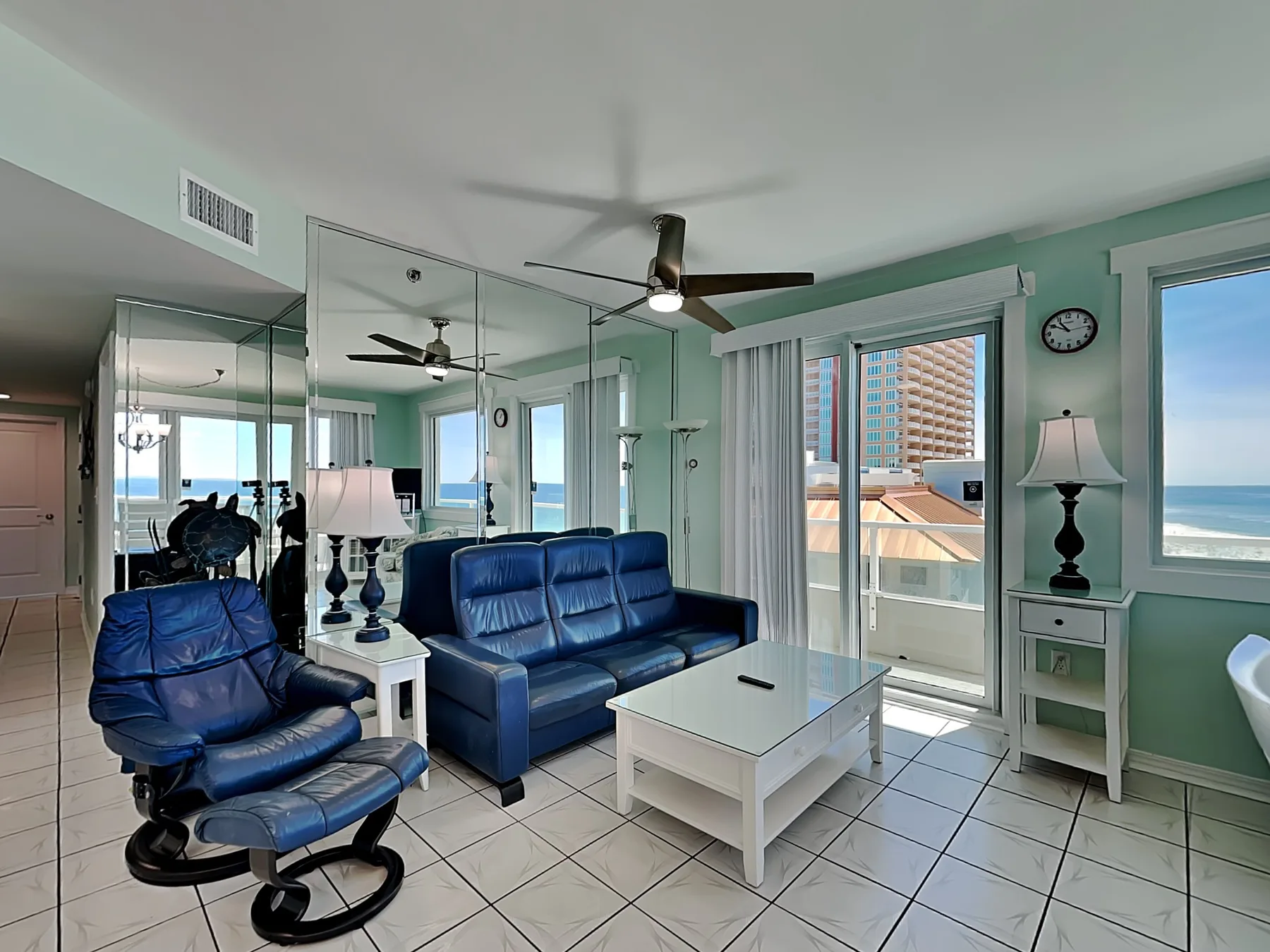 A living room with blue seating, a white coffee table, and mirrored walls.