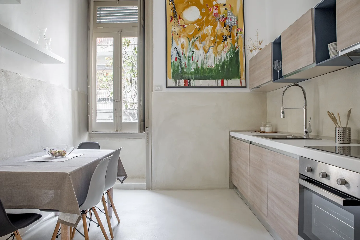 A bright kitchen and dining area with a table beside a tall window.