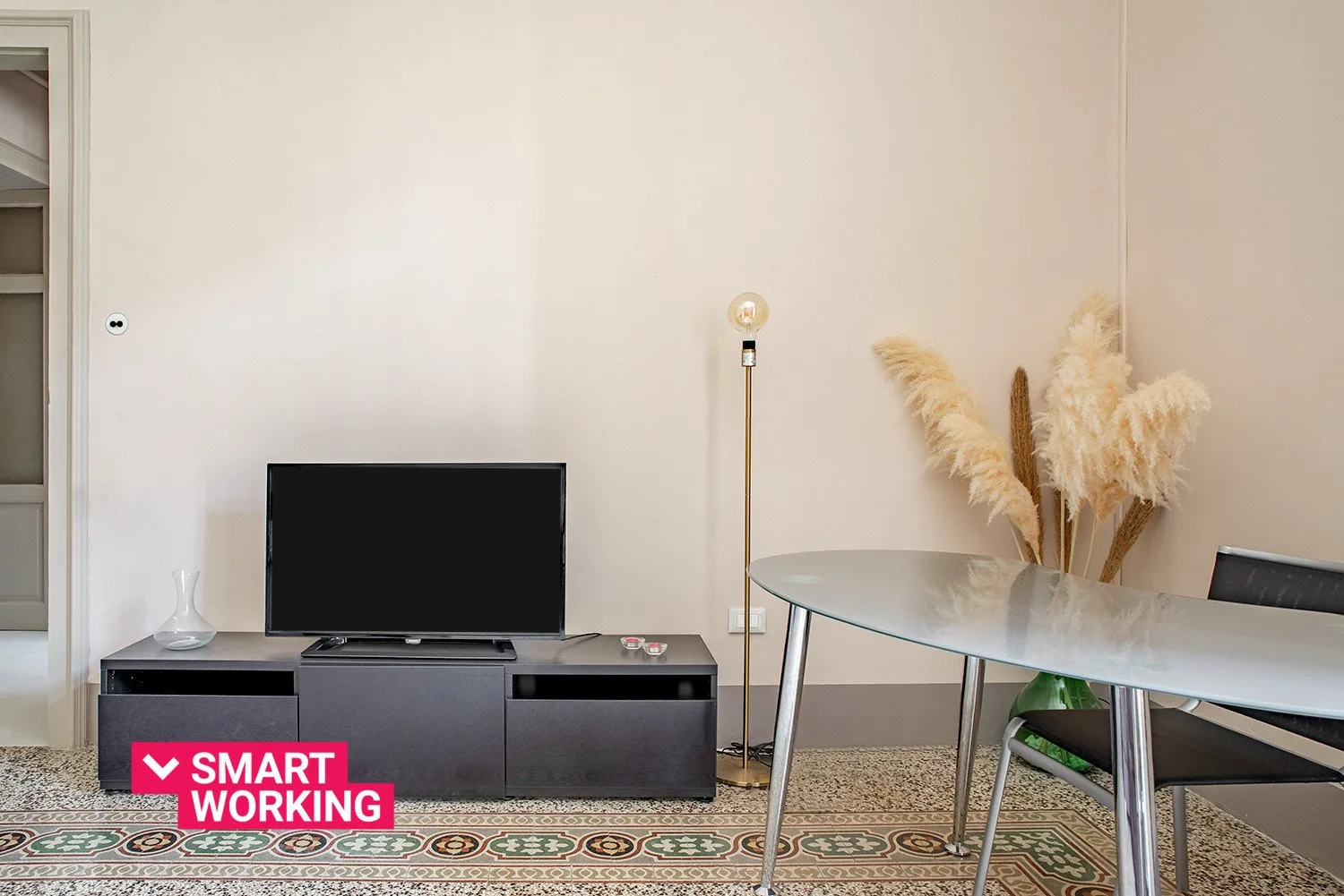 Una sala de estar con un televisor, un mueble bajo y una mesa de vidrio.