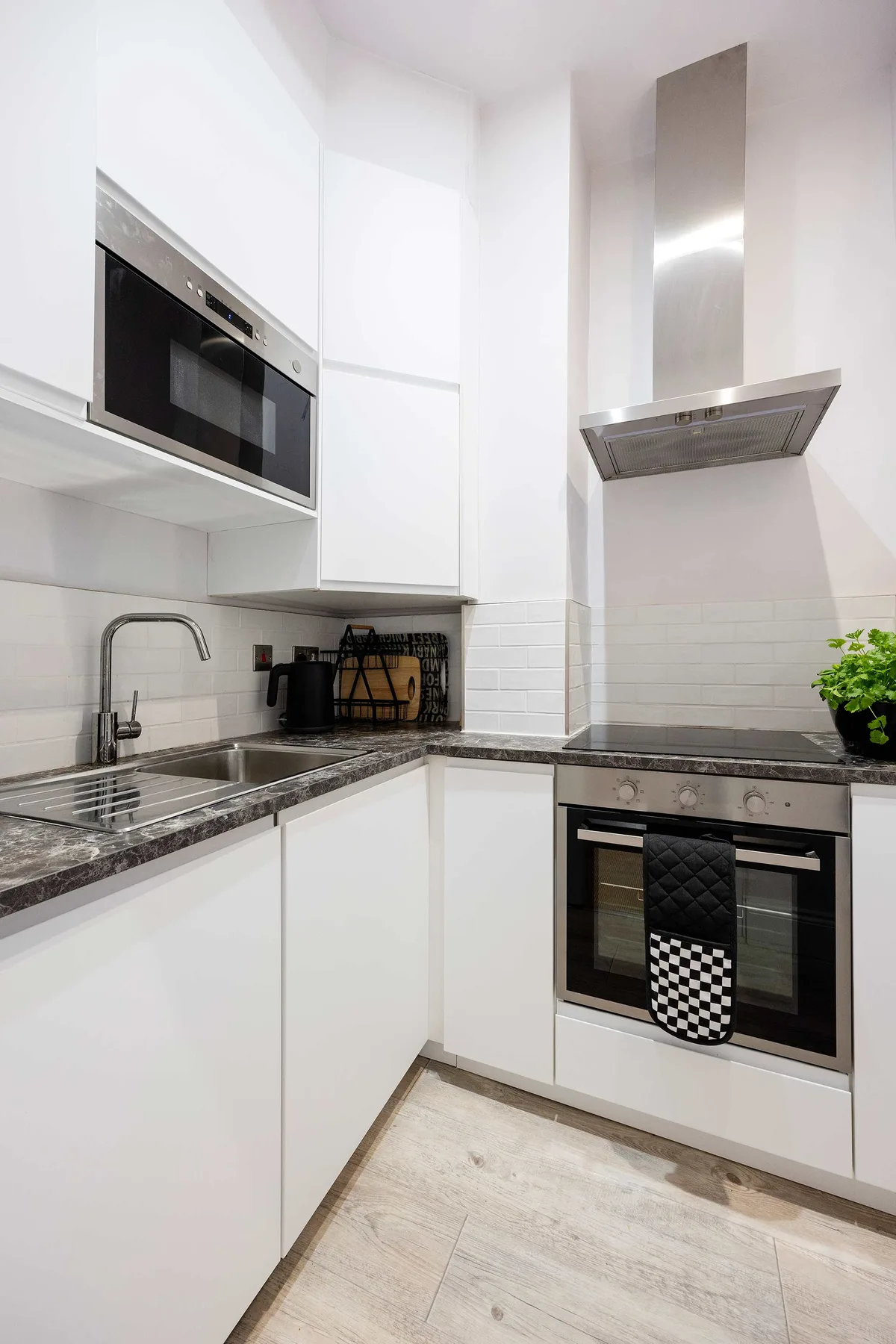 A bright modern kitchen with white cabinets, dark countertops, and built-in appliances.