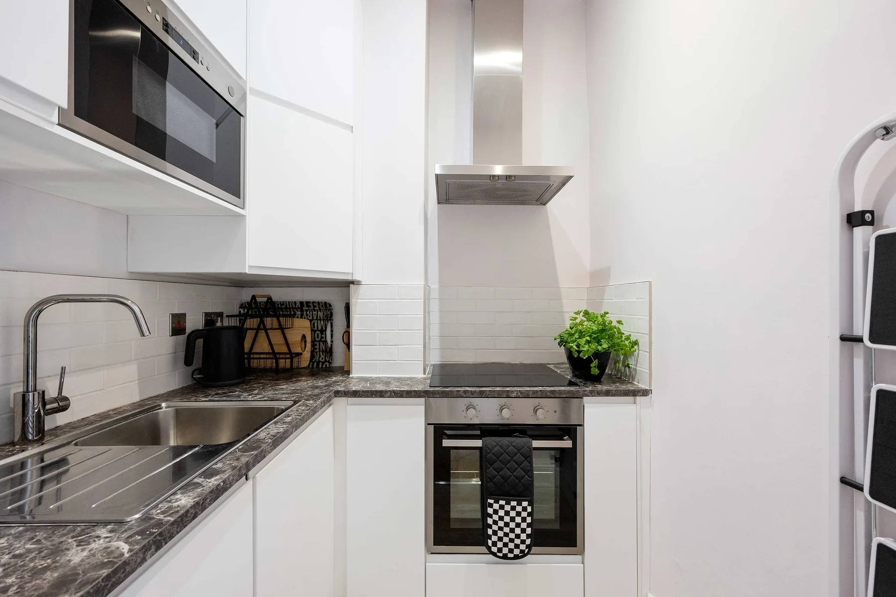 A modern kitchen with white cabinetry, a sink, and a cooktop.