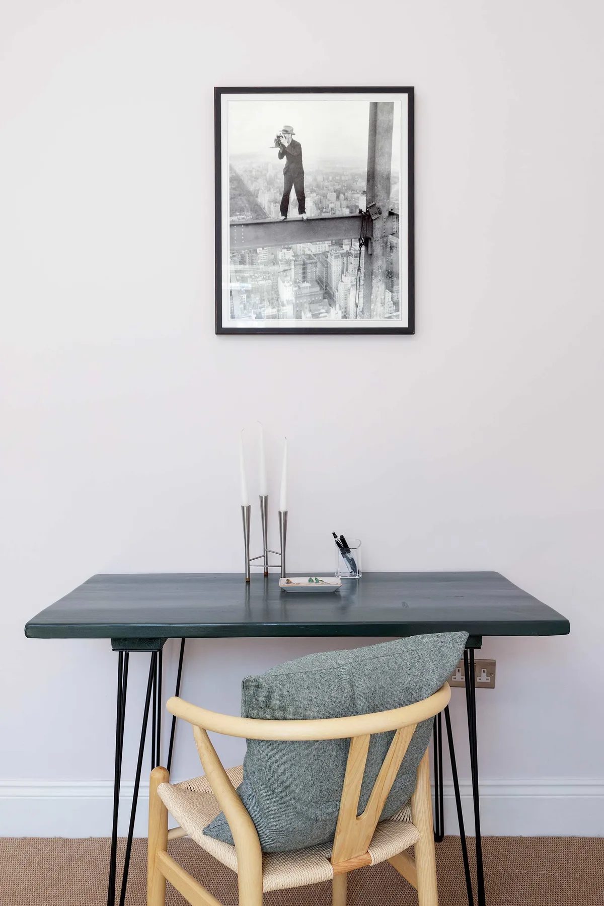 A small desk with a wooden chair sits beneath a framed black-and-white photograph.