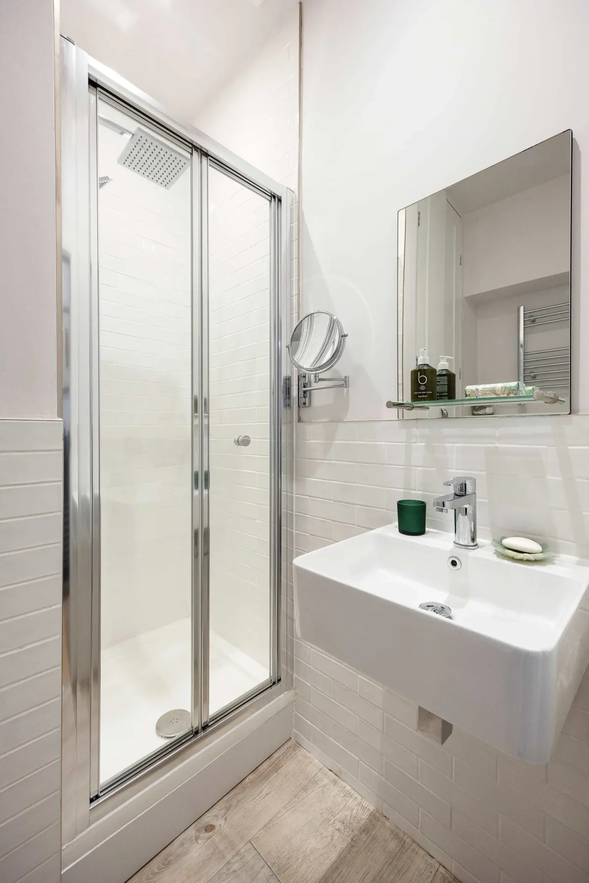A bright bathroom with a glass shower and a wall-mounted sink.