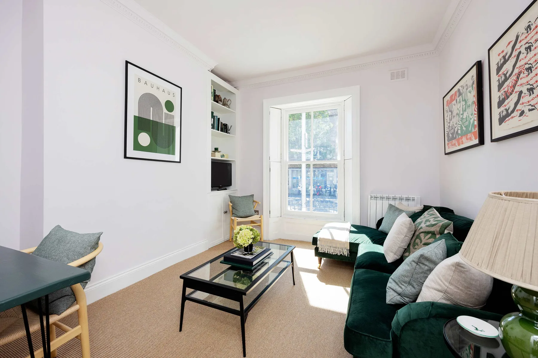 A bright living room with green seating, a coffee table, and a large window.