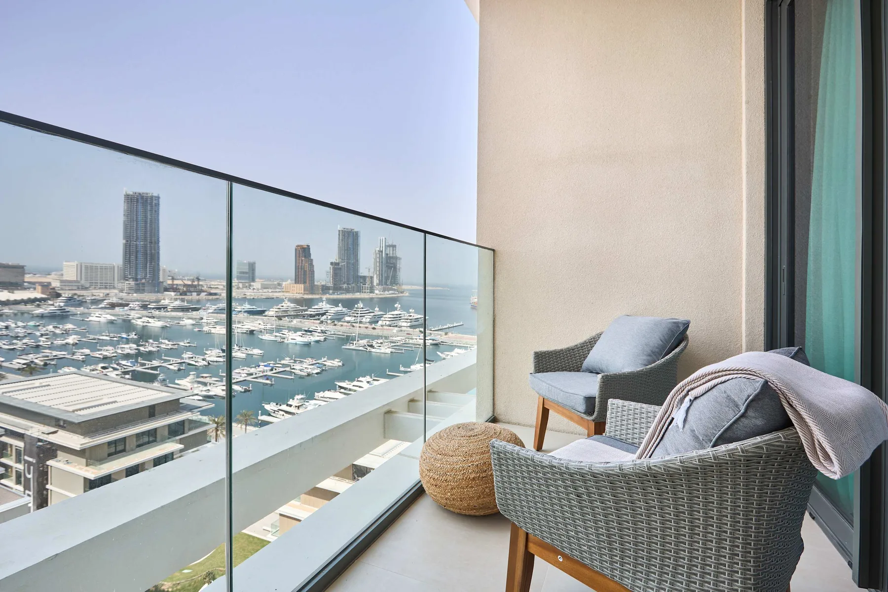 A balcony seating area overlooks a marina and waterfront skyline.
