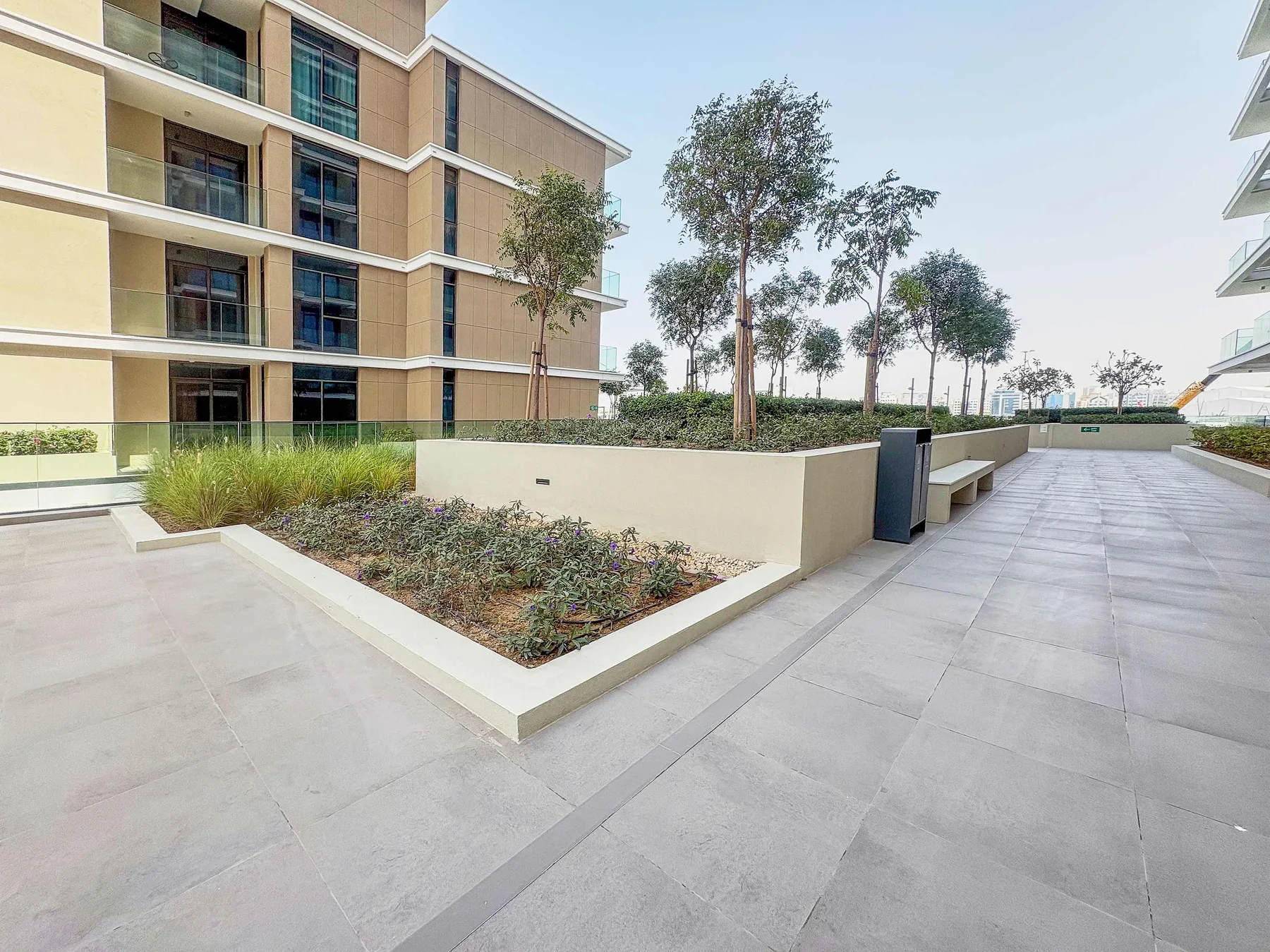 A paved courtyard surrounds a raised garden bed with trees and shrubs.