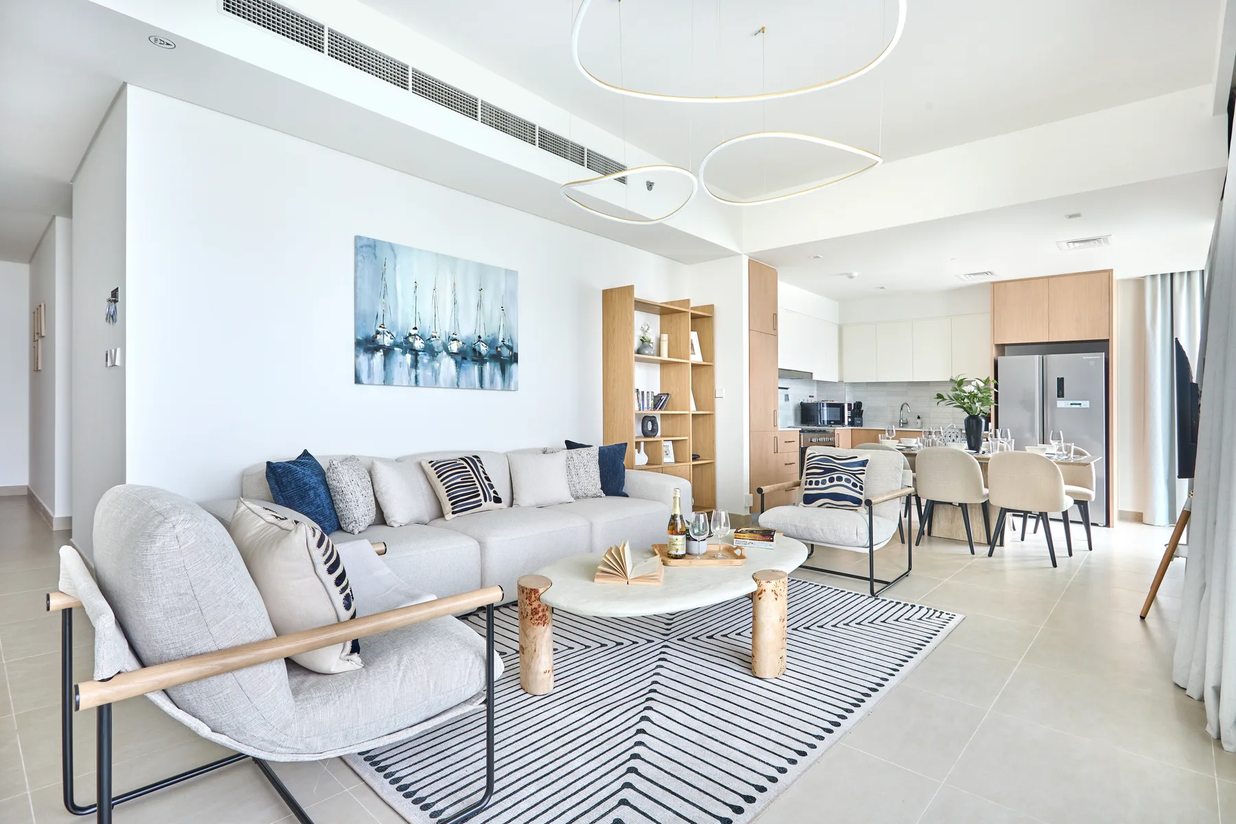 A bright open-plan living room with seating and a dining area beside the kitchen.