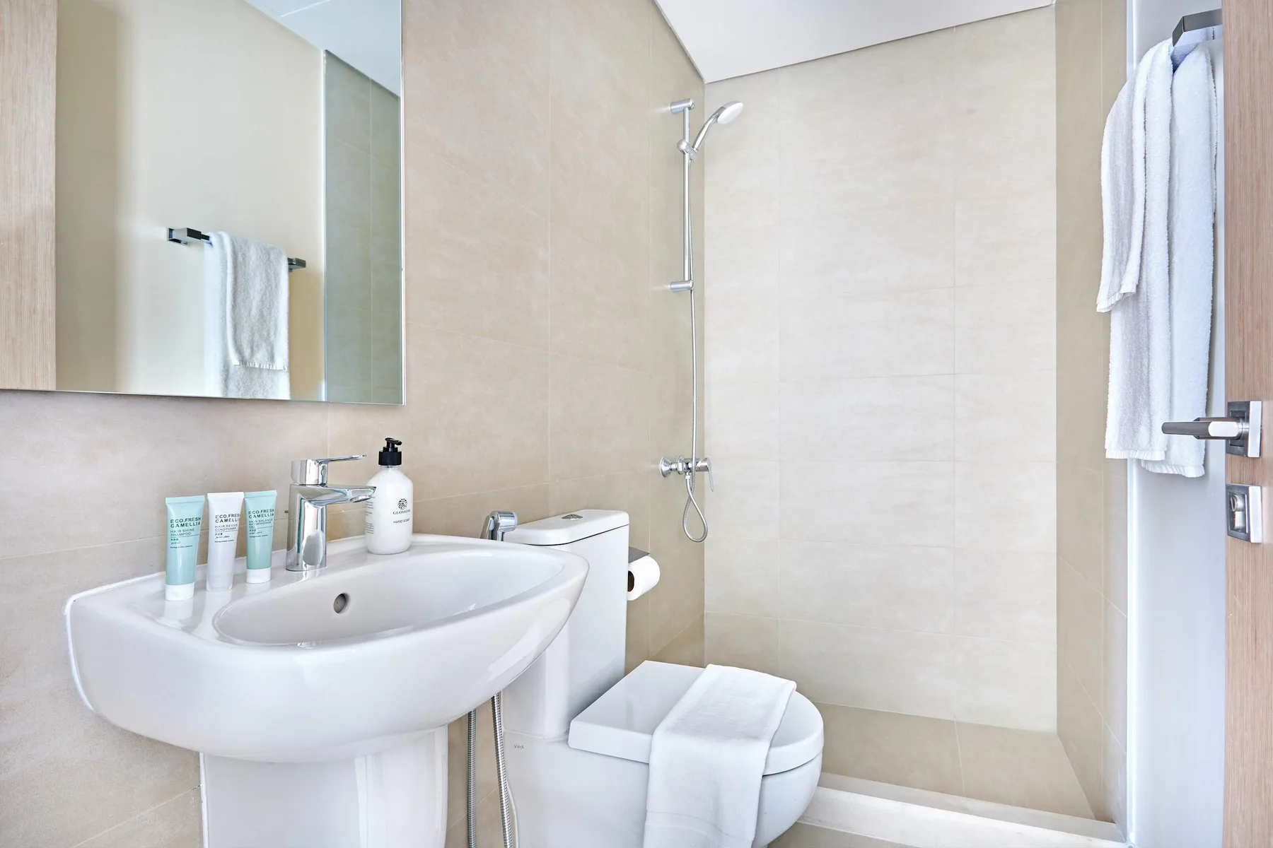 A bright bathroom with a sink, toilet, and shower.