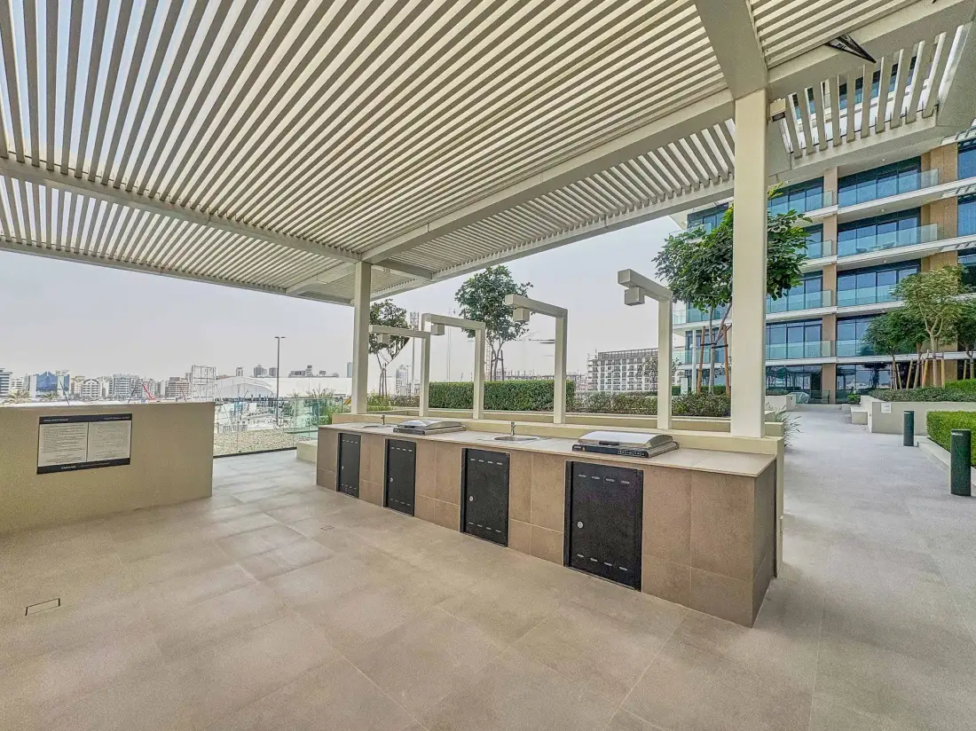 A covered outdoor counter area with a slatted roof and nearby seating.