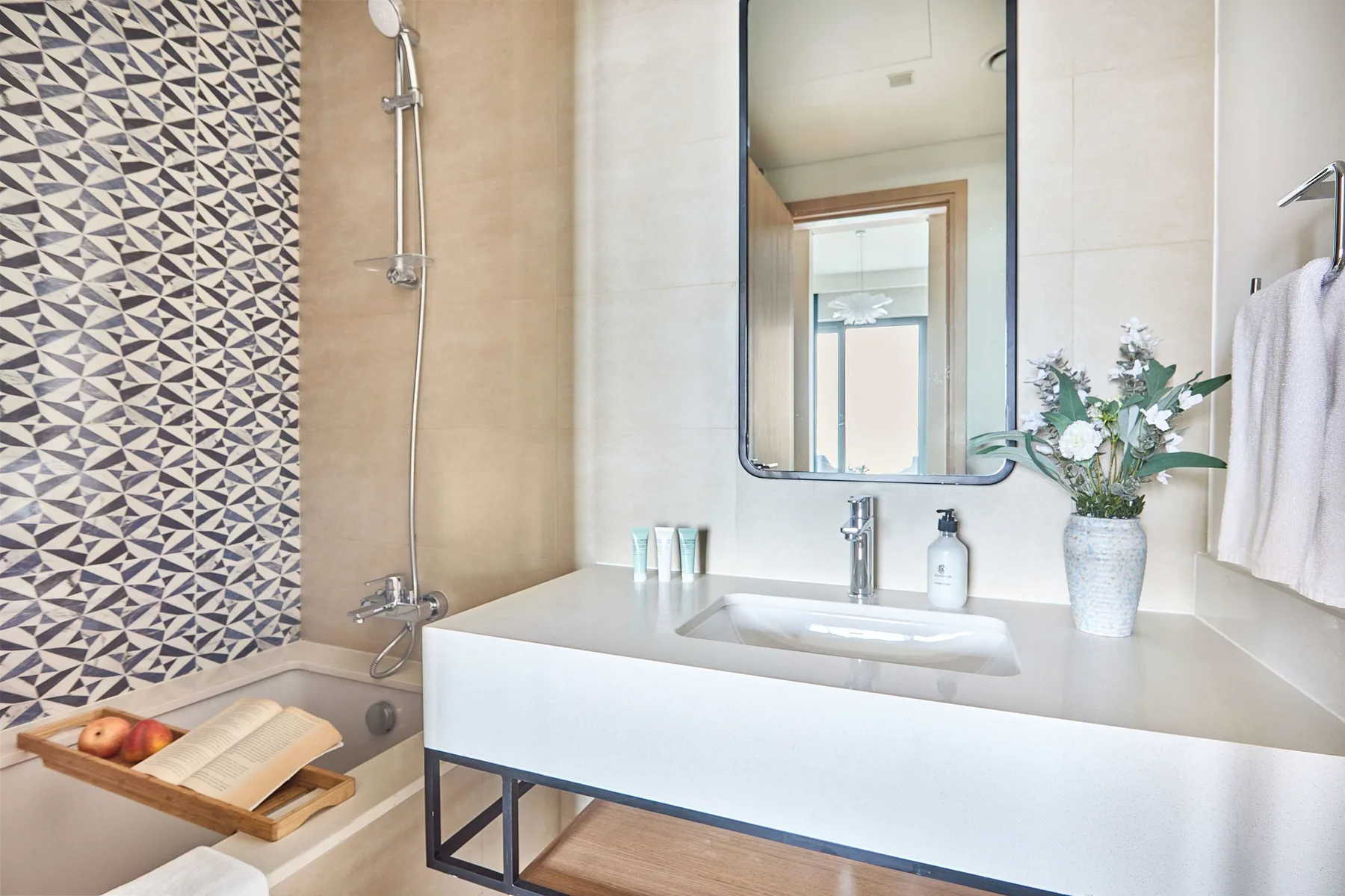 A bathroom vanity with a sink, mirror, and patterned wall tile.
