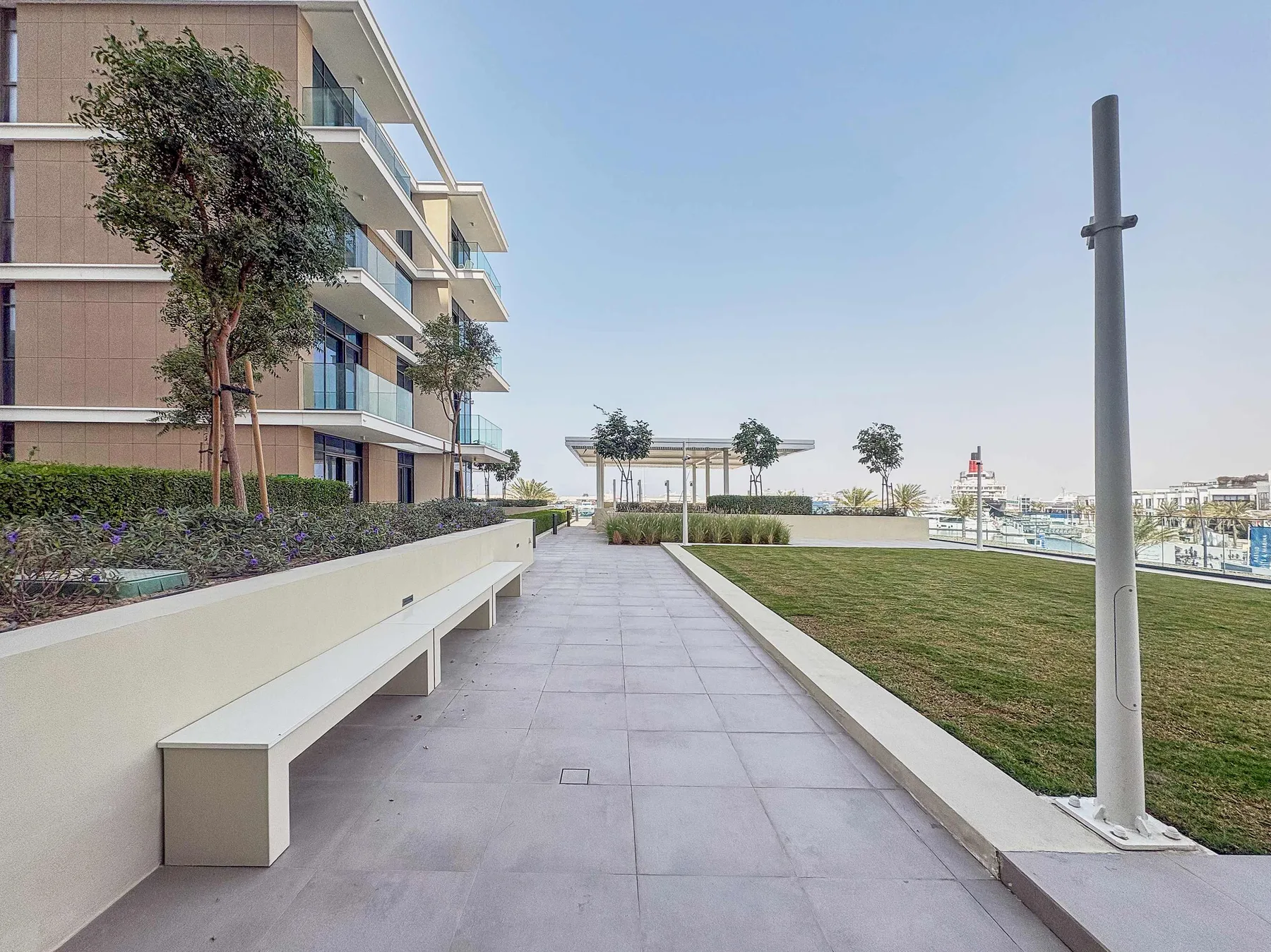 A paved walkway beside a landscaped lawn and modern building.