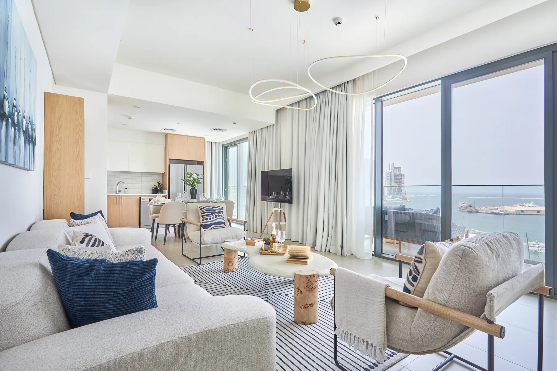 A bright living room opens onto a balcony, with a dining area beyond.