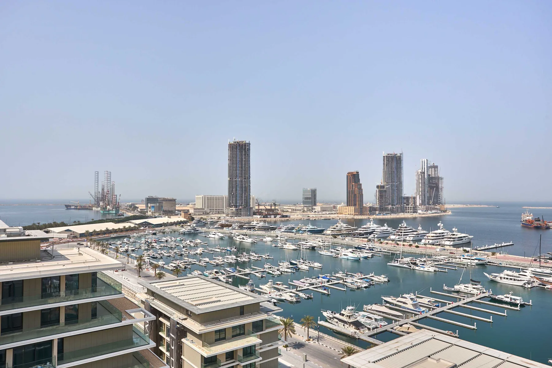 A marina filled with boats sits beside modern high-rise buildings along the waterfront.