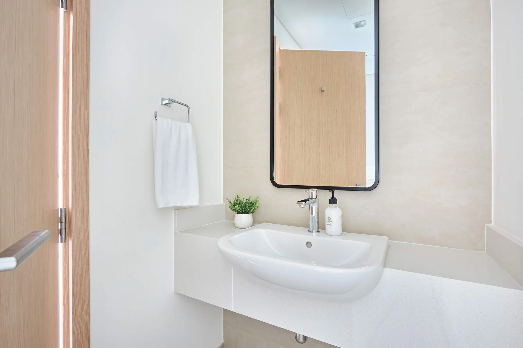 A bright bathroom with a wall-mounted sink, mirror, and towel.