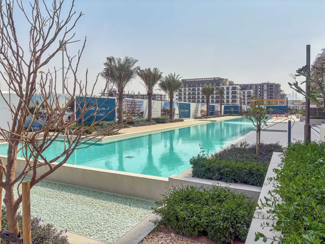 A landscaped outdoor swimming pool sits in front of modern residential buildings.