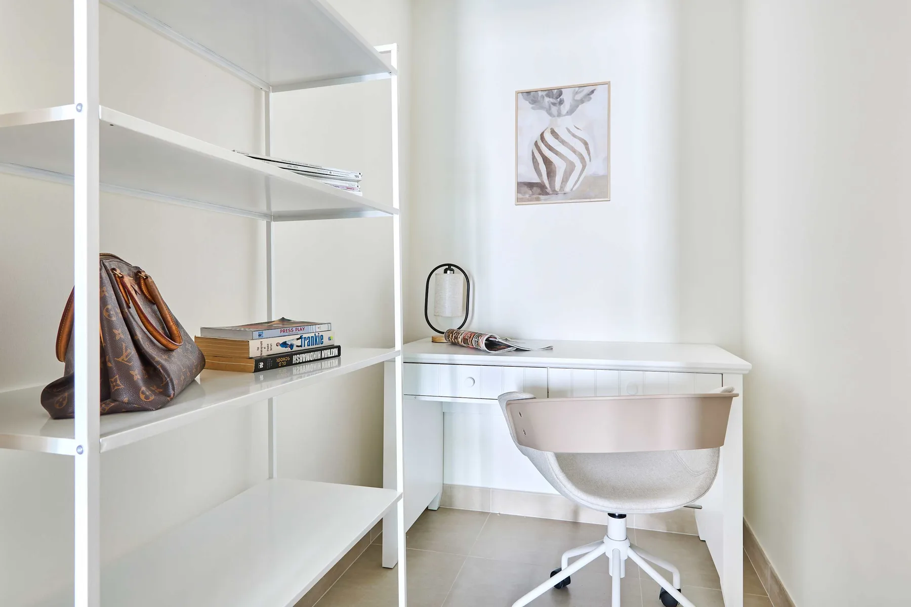 A bright workspace with a white desk, chair, and open shelving.