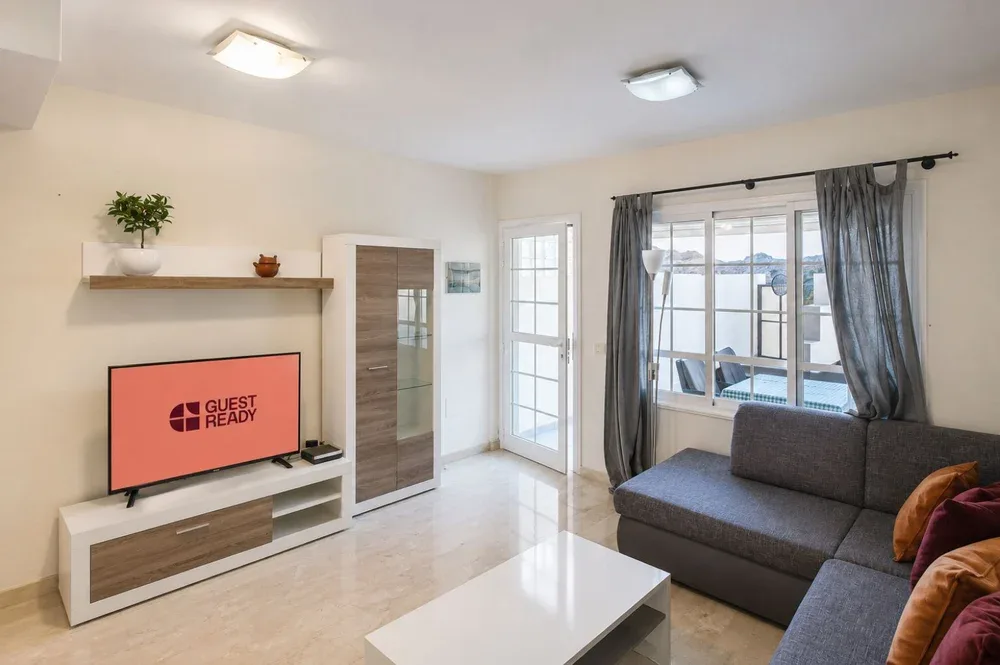 Una sala luminosa con televisor, asientos y una ventana amplia.