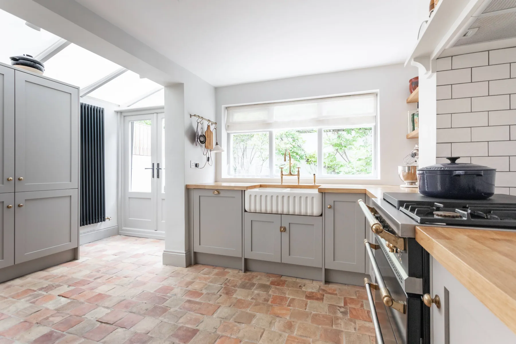 A bright kitchen with gray cabinets, a tiled floor, and a large window.