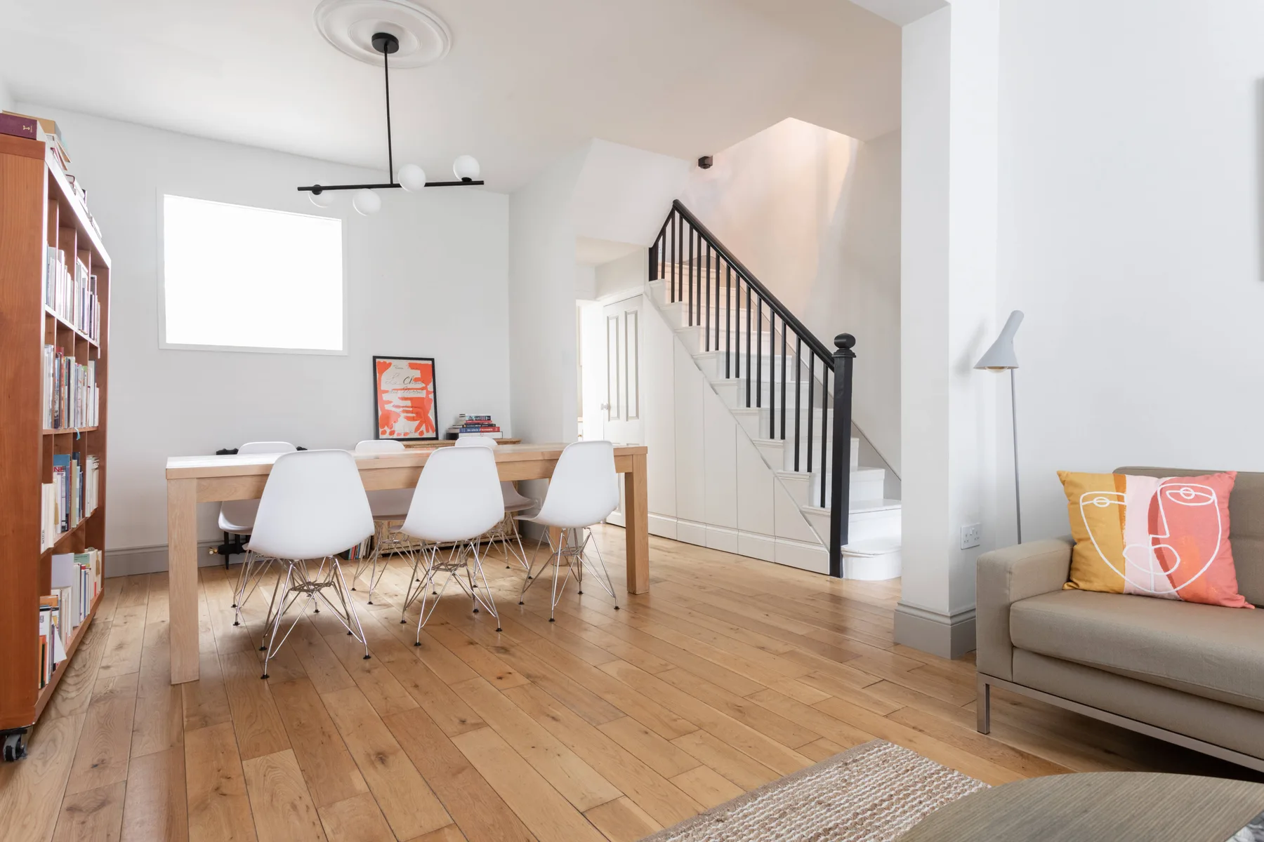 A bright dining area with a table beside a staircase and living room seating.