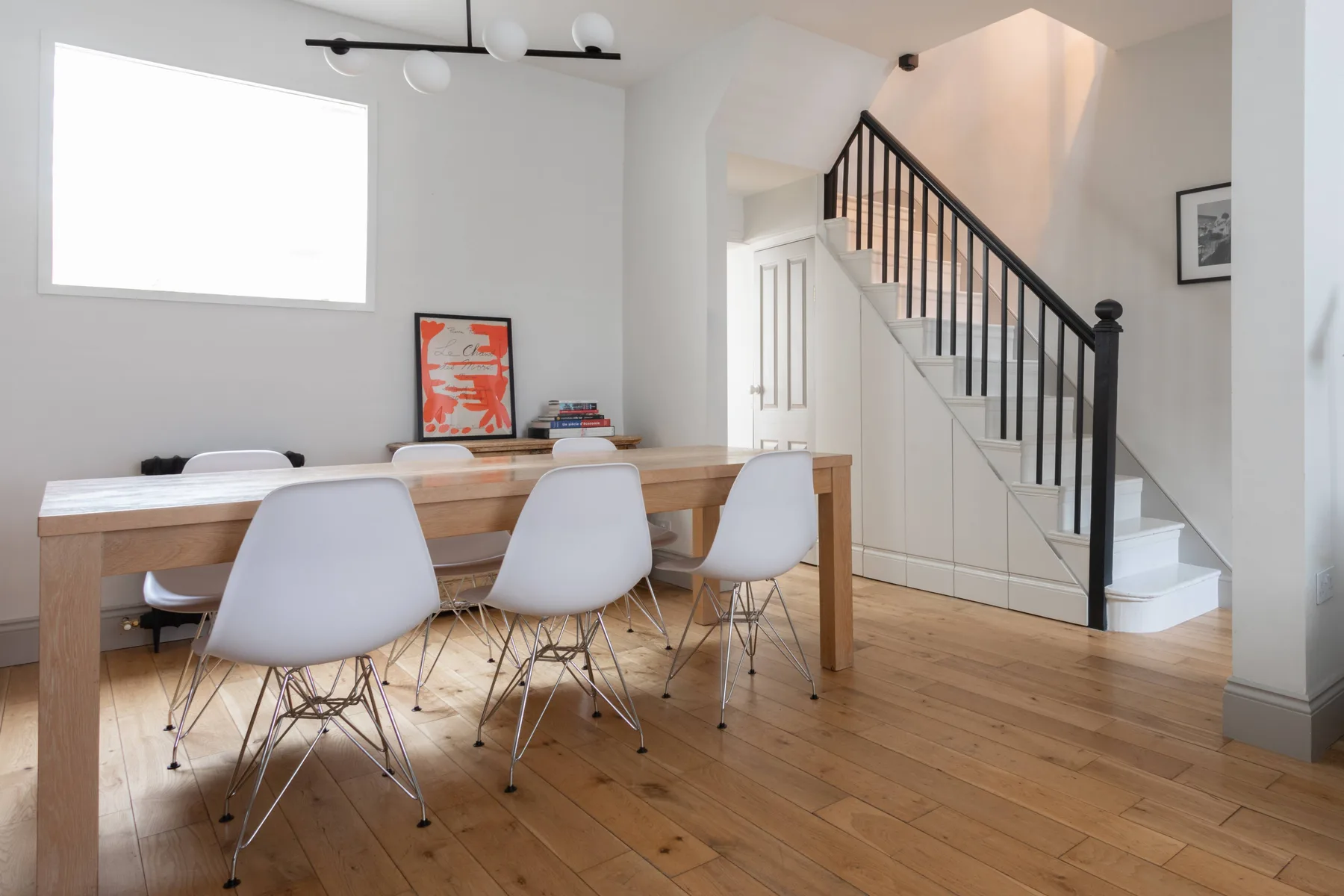 A dining area with a wooden table and chairs beside a staircase.