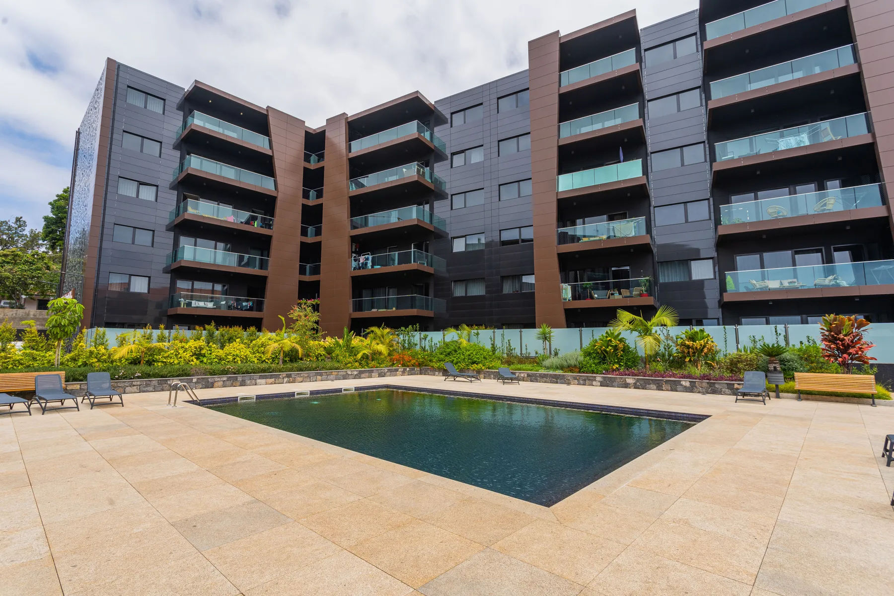 An apartment building overlooks a courtyard pool and paved terrace.