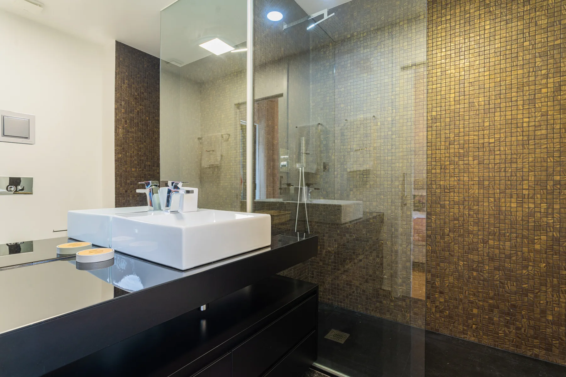 A modern bathroom with a white vessel sink beside a glass shower.