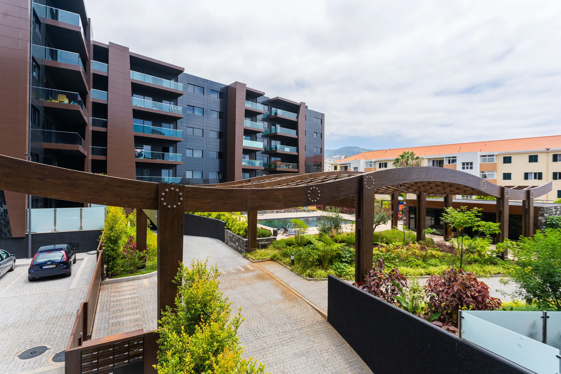 An apartment complex with balconies overlooks landscaped grounds and a paved walkway.