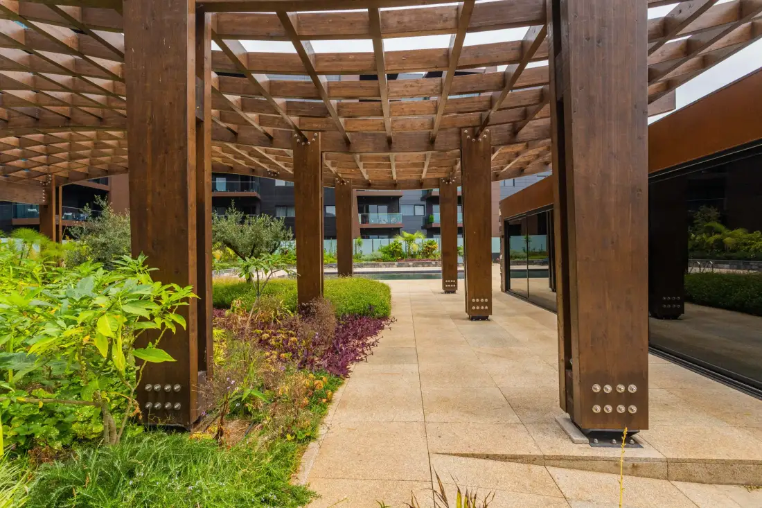 A landscaped outdoor walkway runs beneath a wooden pergola.