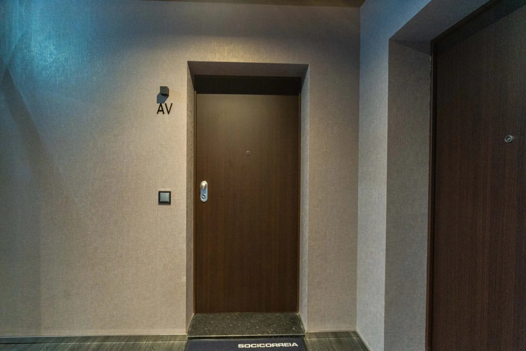 An indoor hallway with two dark wooden doors.