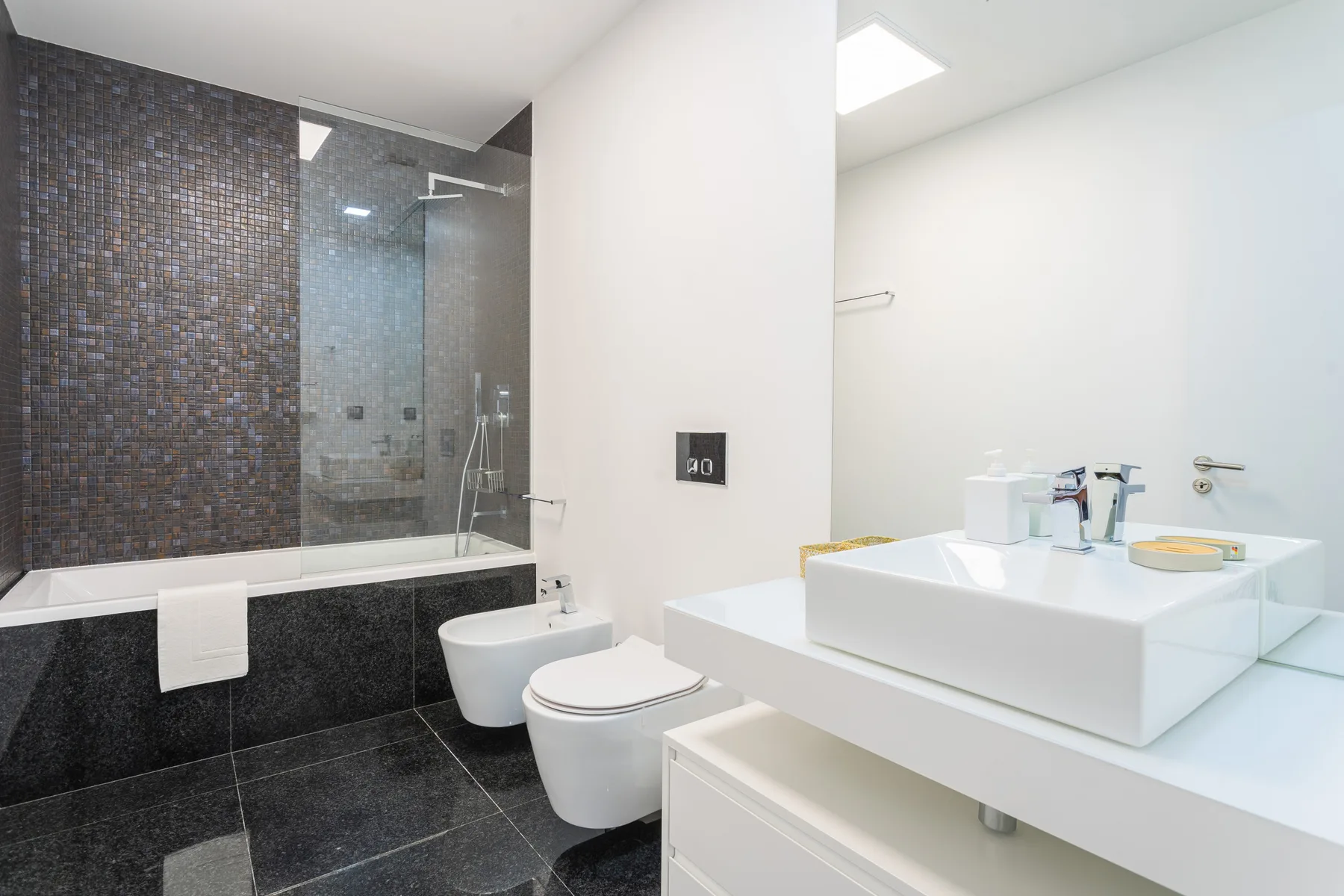 Un baño moderno con bañera, ducha, inodoro y lavabo.