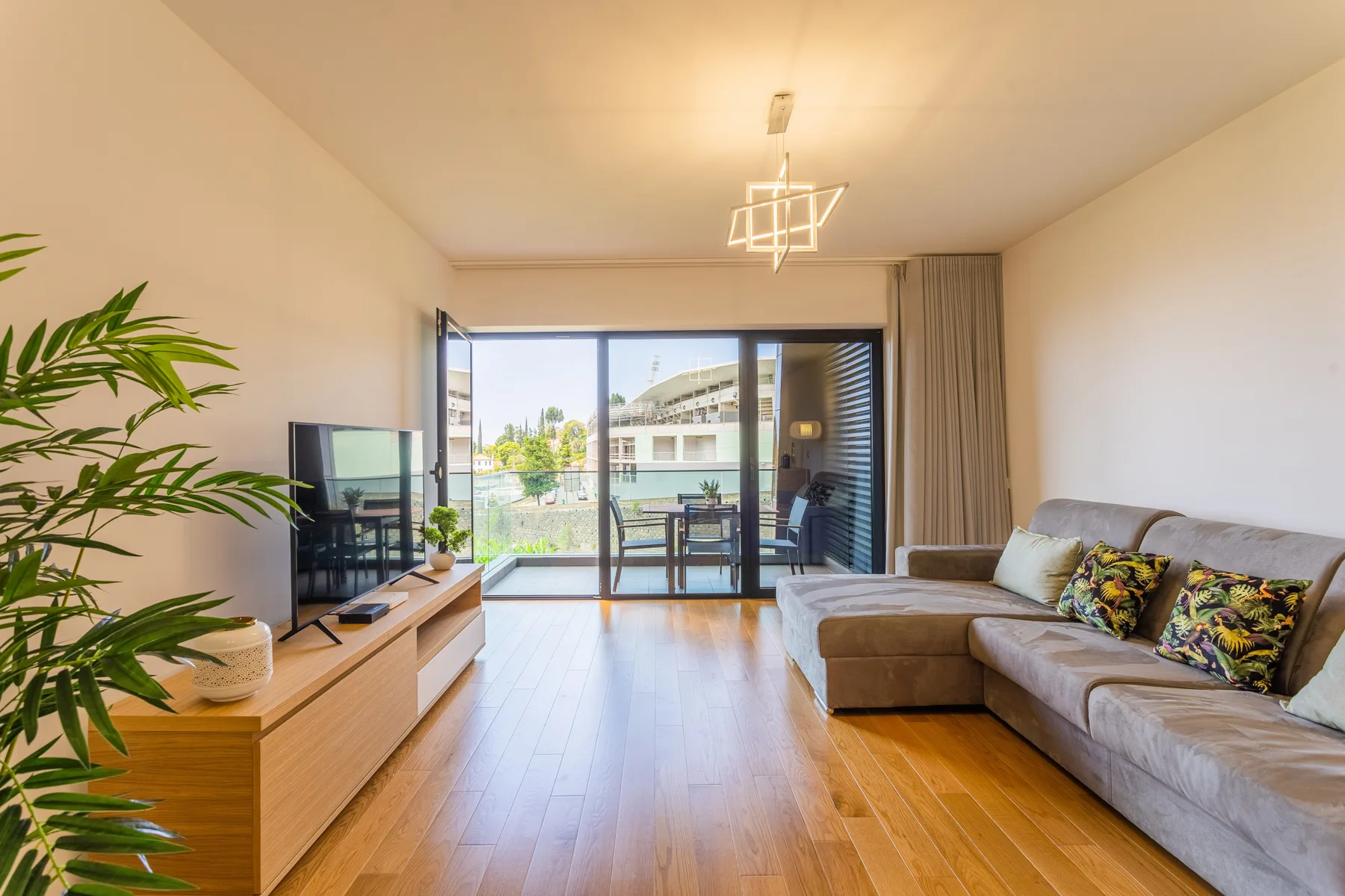 Living room with seating, a television, and glass doors opening onto a balcony.