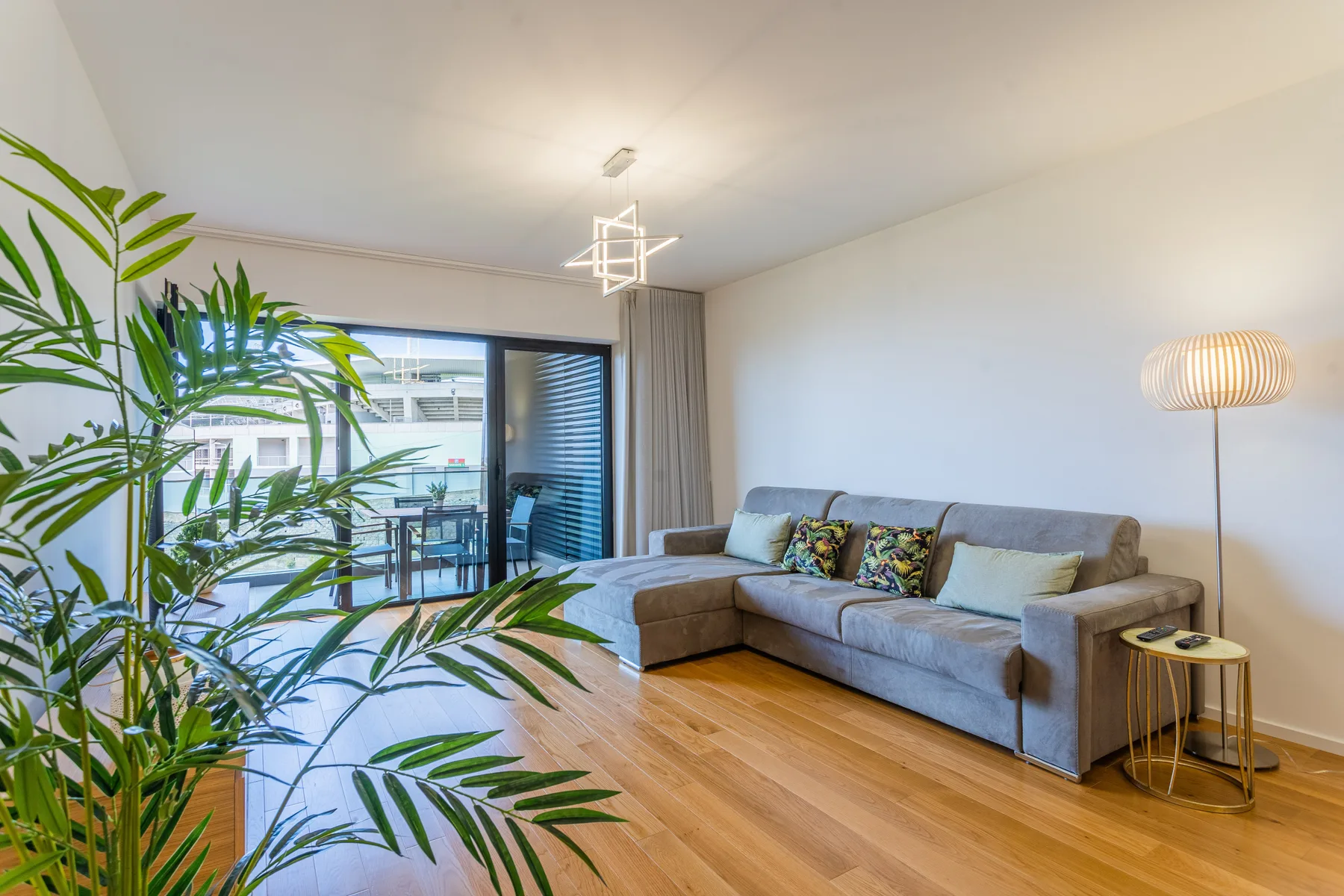 Living room with seating, a floor lamp, and sliding doors opening onto a balcony.