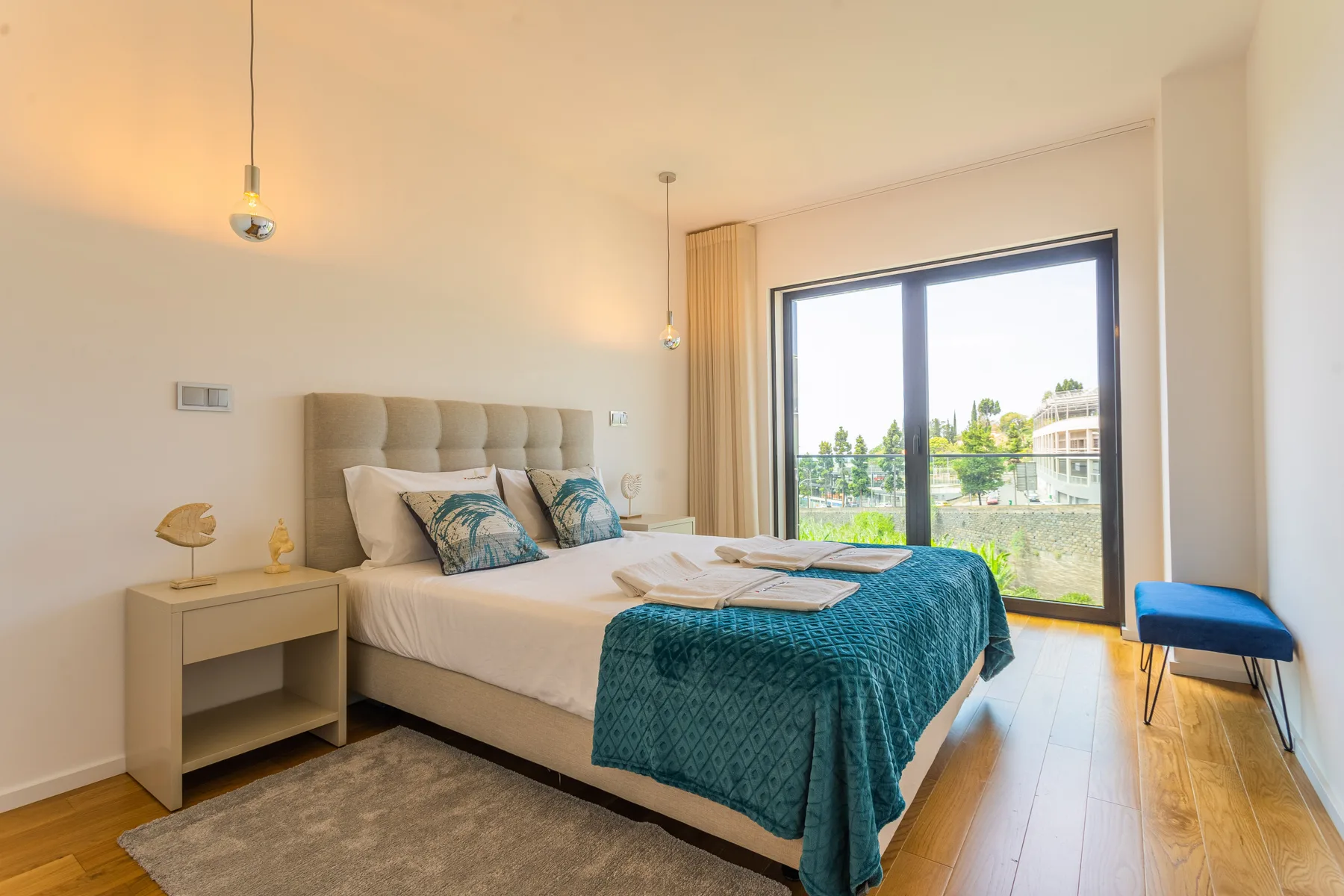 A bedroom with a large bed and a glass door opening onto a balcony.