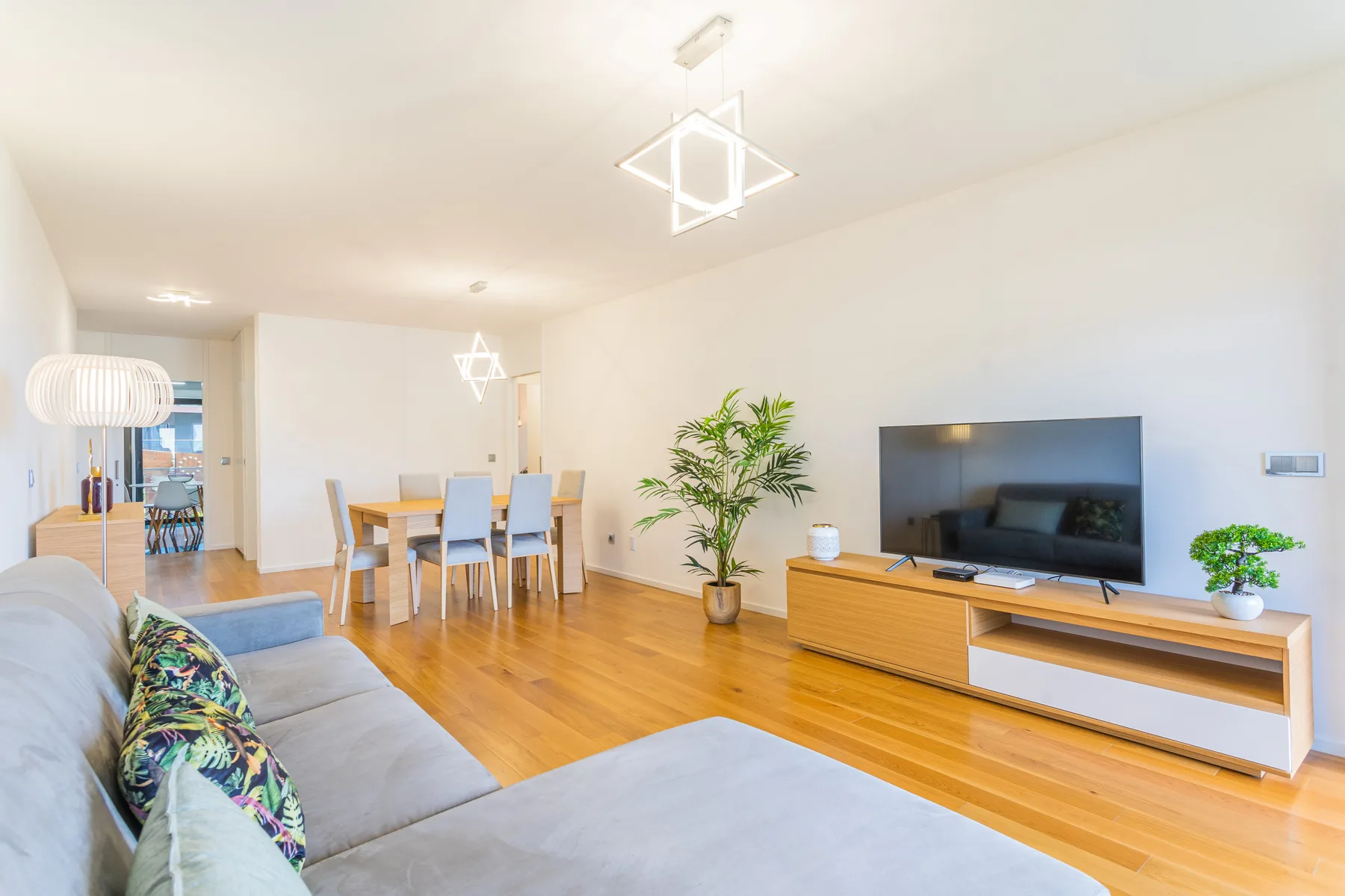 A bright living room with seating, a television, and a dining table.
