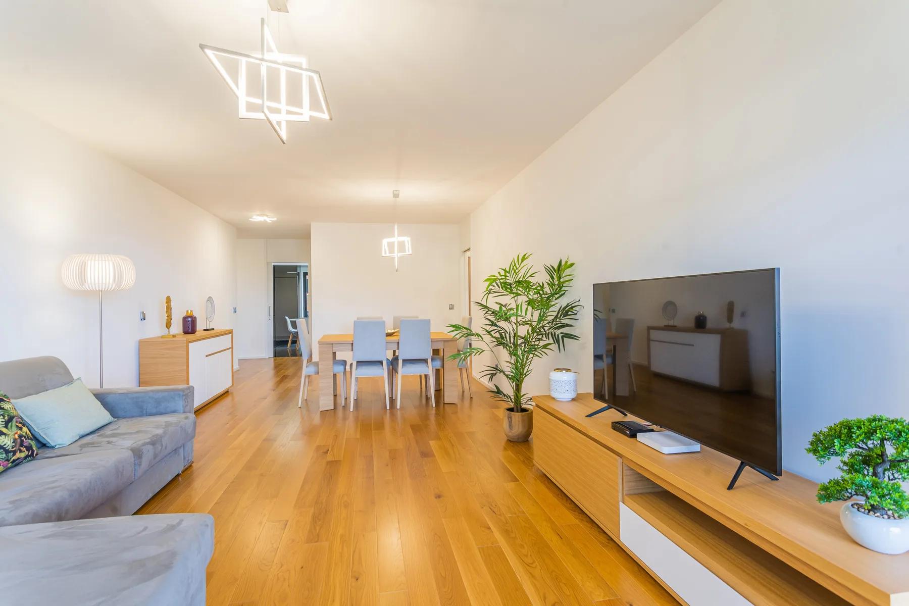 A bright living and dining area with seating, a dining table, and a television.