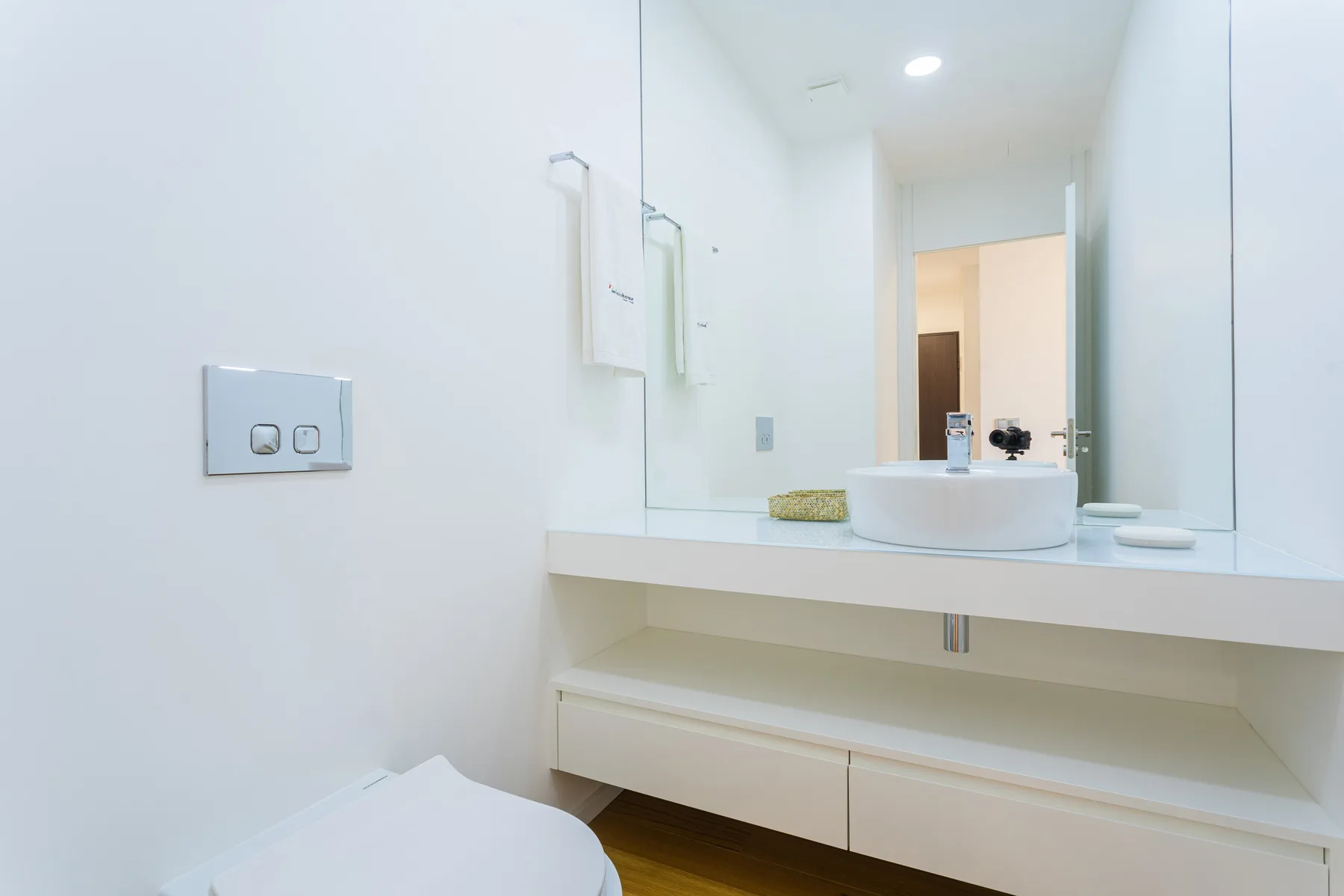 A bright bathroom with a wide vanity, sink, and large mirror.
