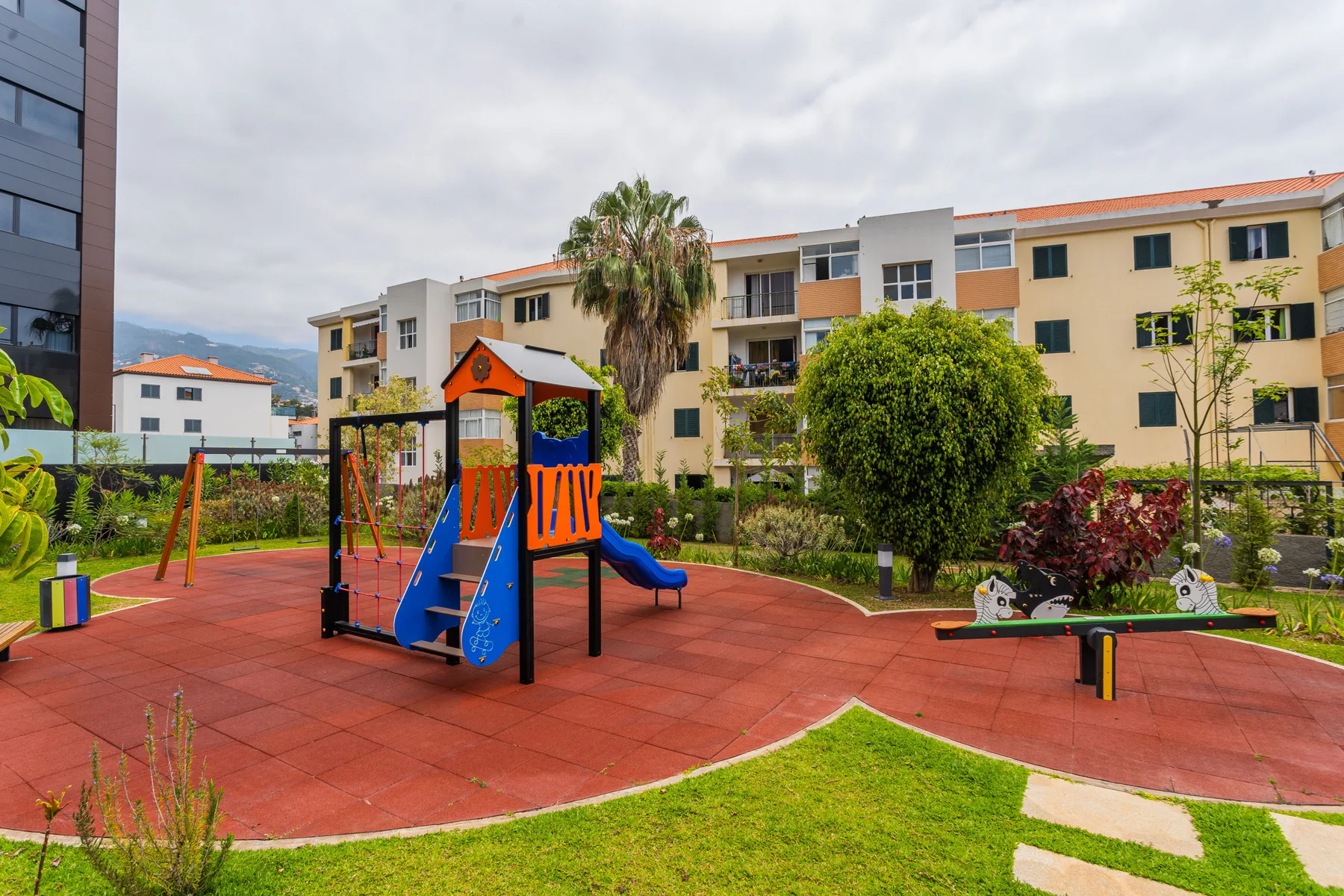 An outdoor playground with colorful play equipment and landscaped greenery.