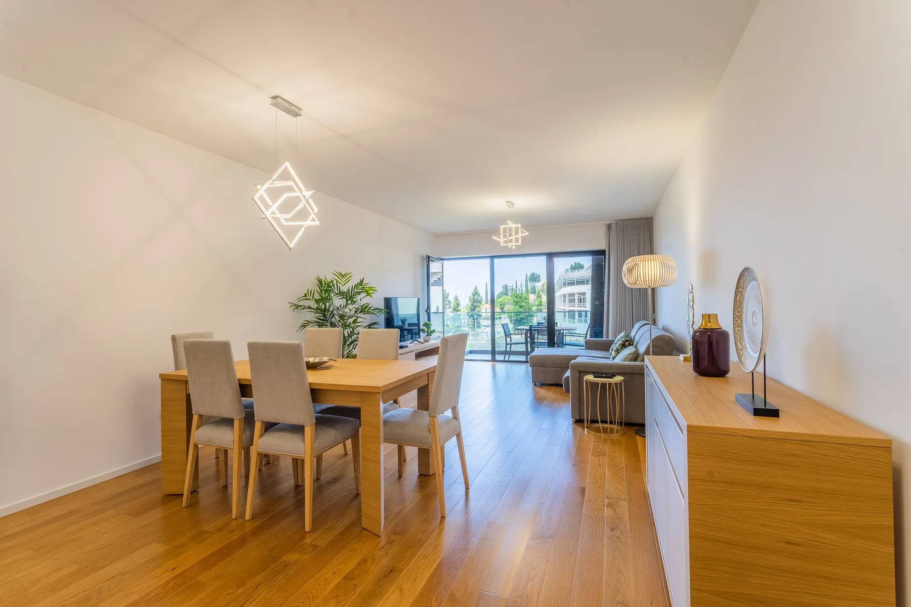 A bright living and dining area opens onto a balcony through glass doors.