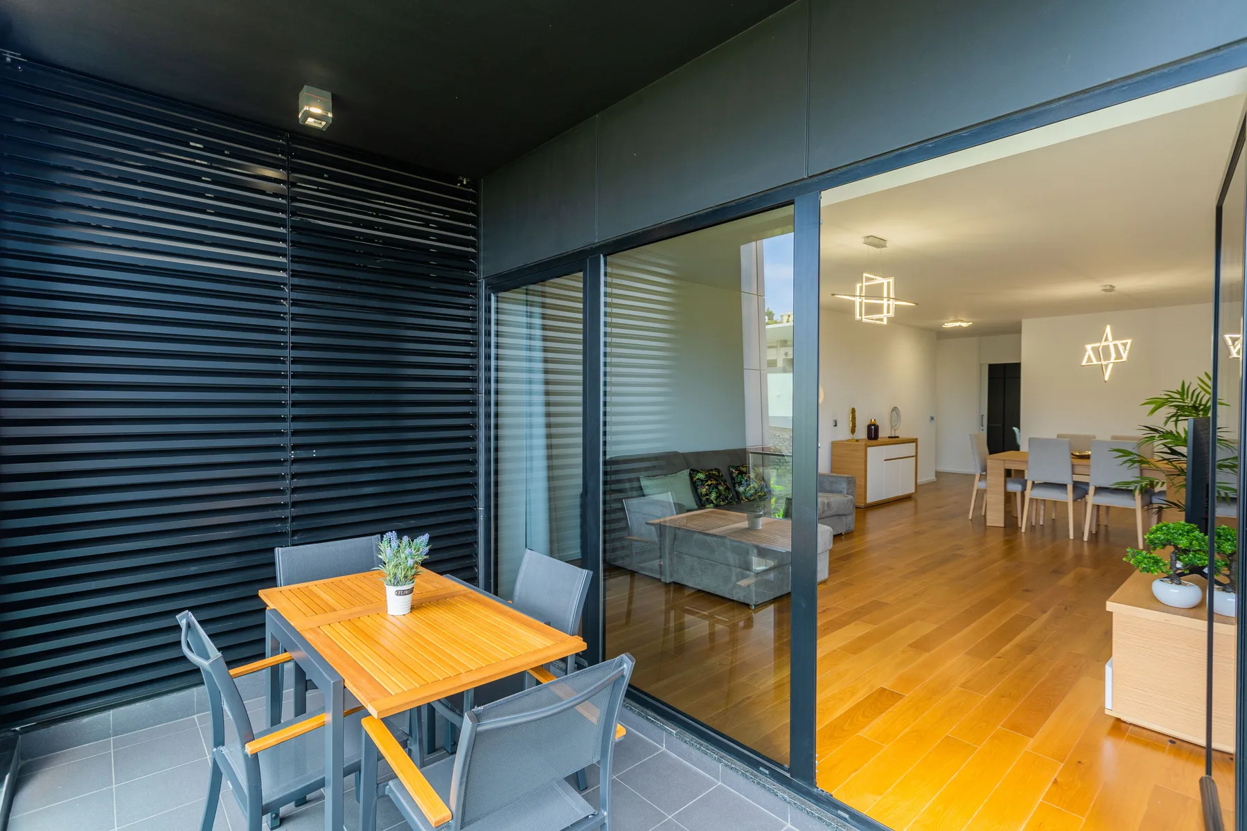 A balcony dining area with a table and seating overlooks a bright interior.