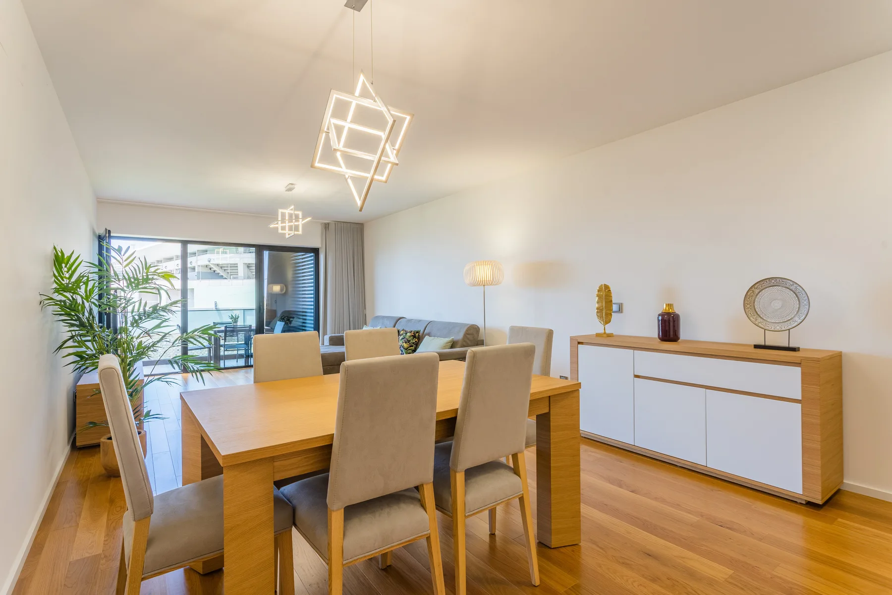 A dining area with a wooden table and chairs beside a bright living space.