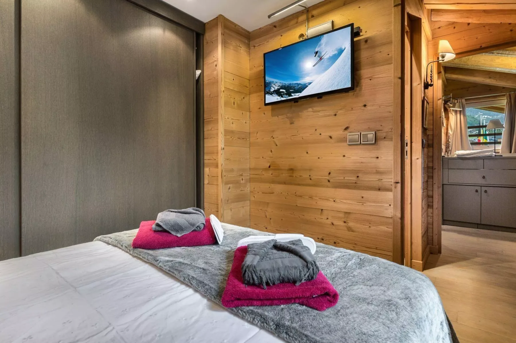 Un dormitorio con una cama y un televisor montado en la pared.
